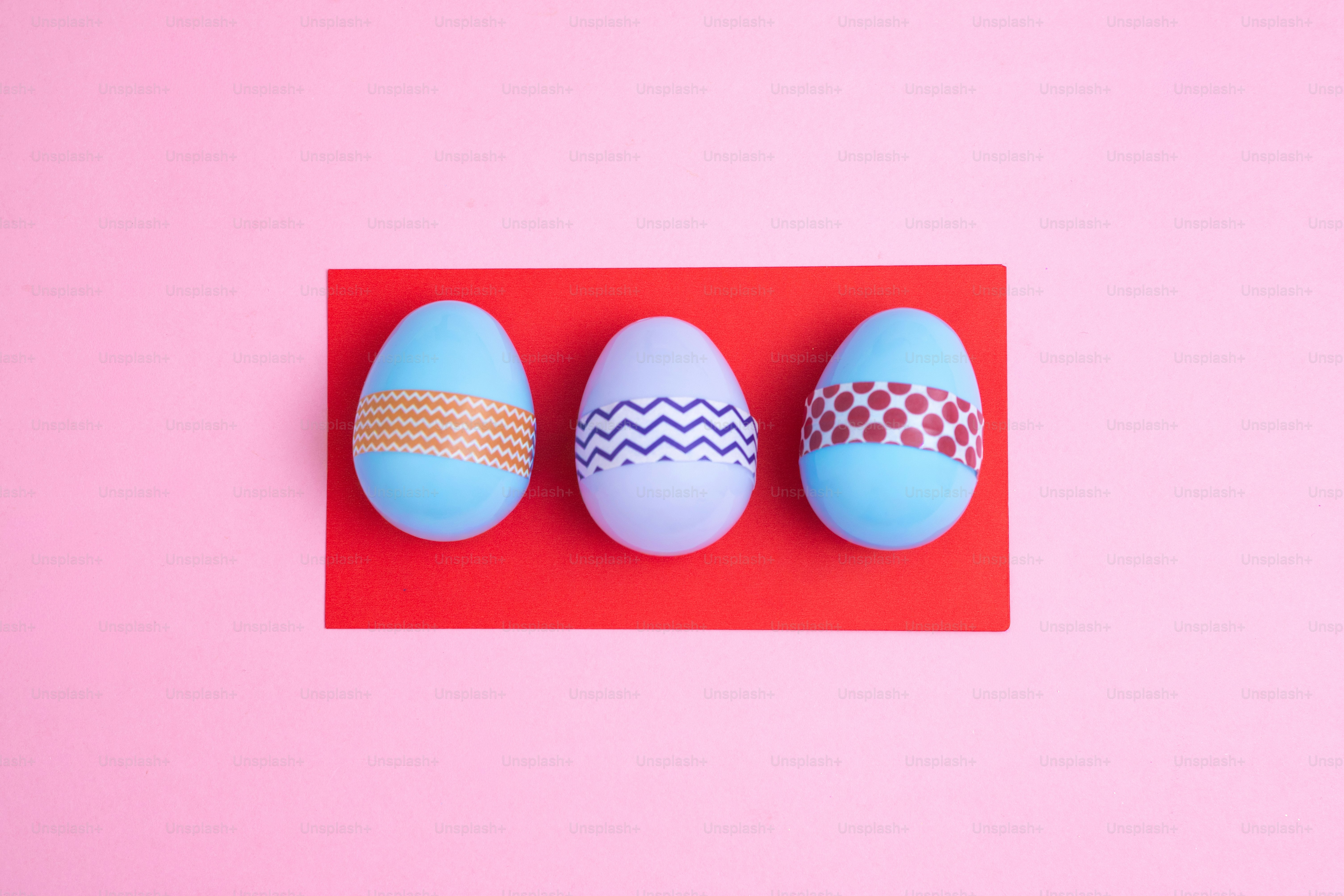 Tiga telur paskah biru dan ungu dengan selotip dekoratif.