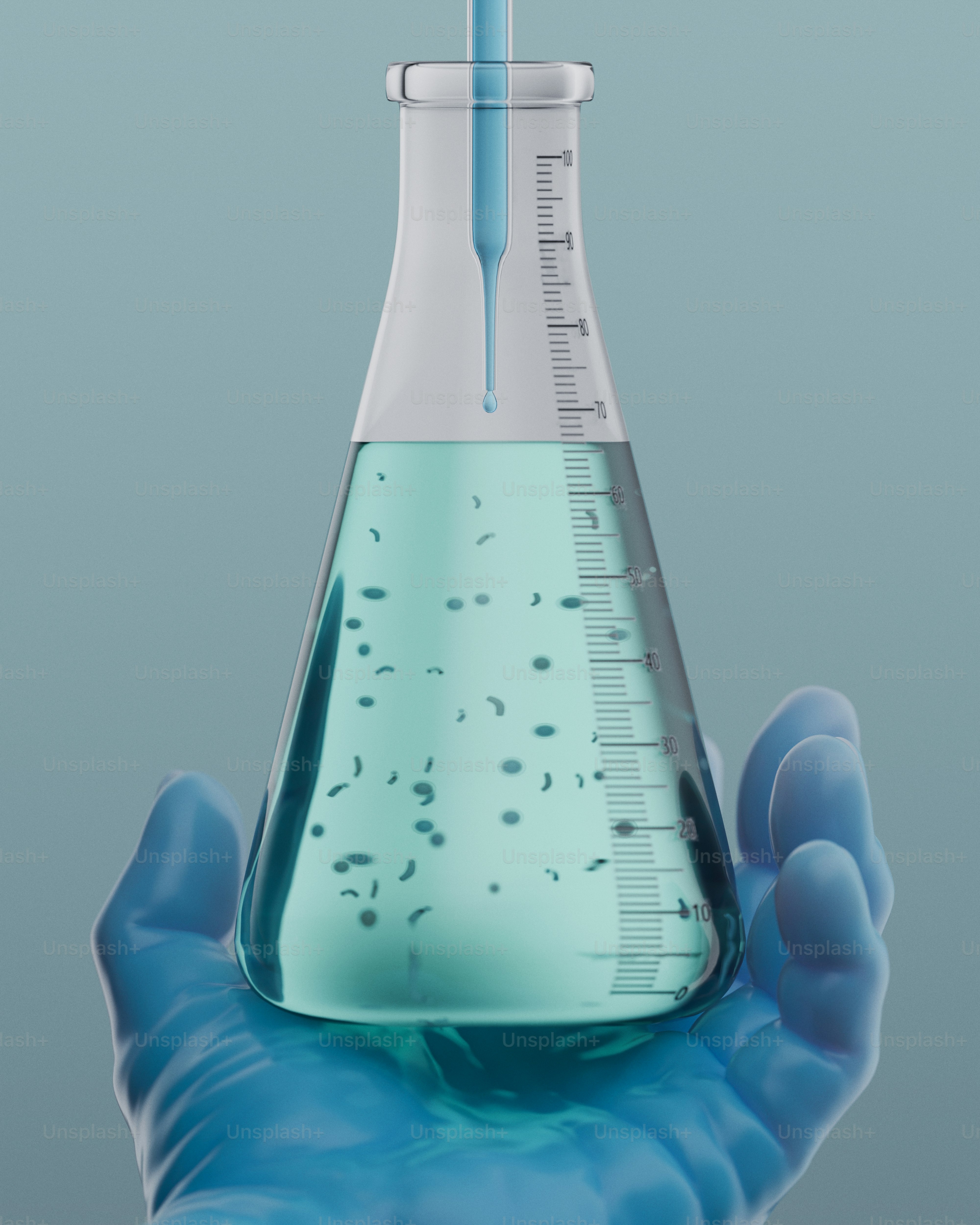 Mão enluvada segura um frasco com líquido azul e pequenas partículas.