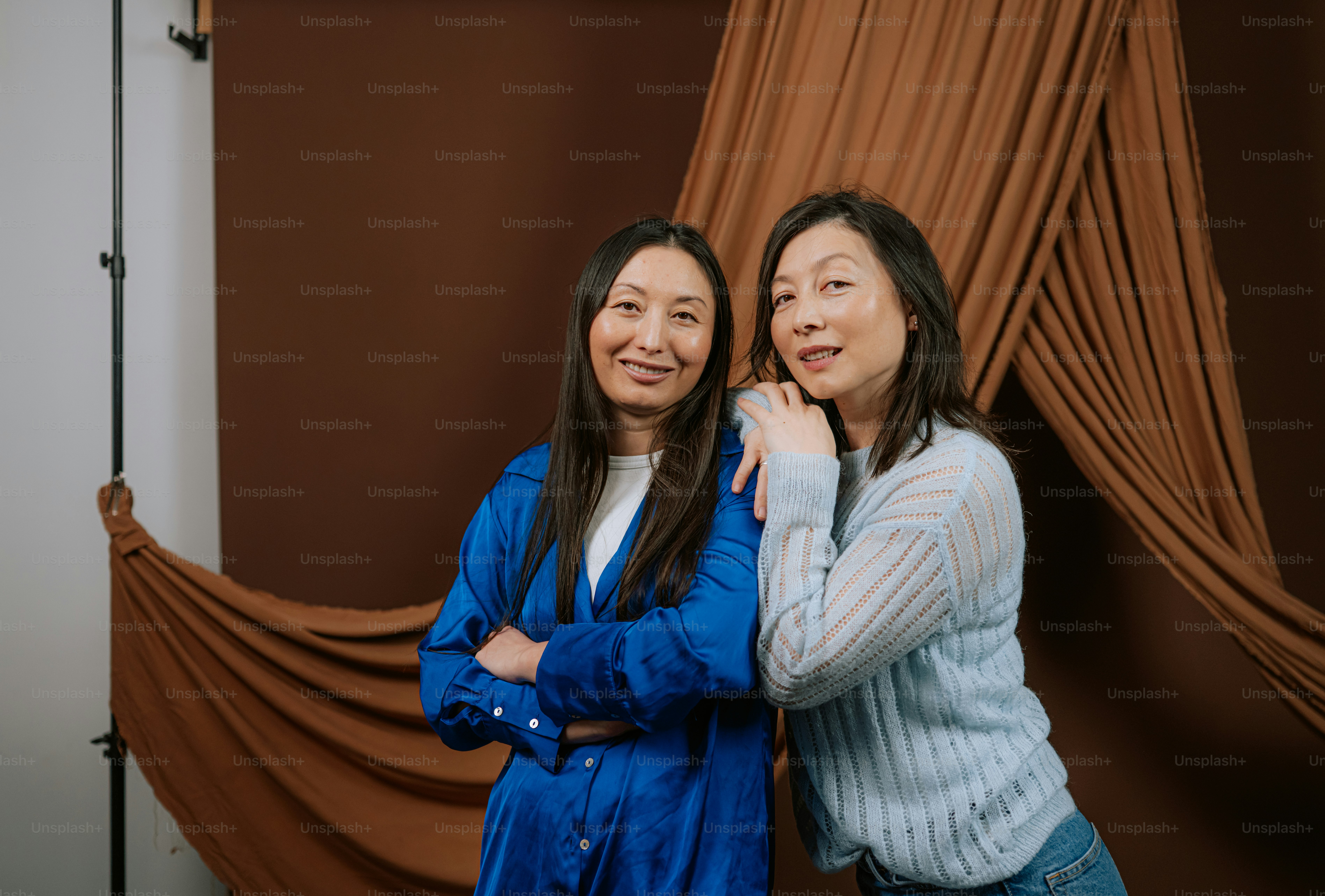 Due donne posano davanti a uno sfondo marrone
