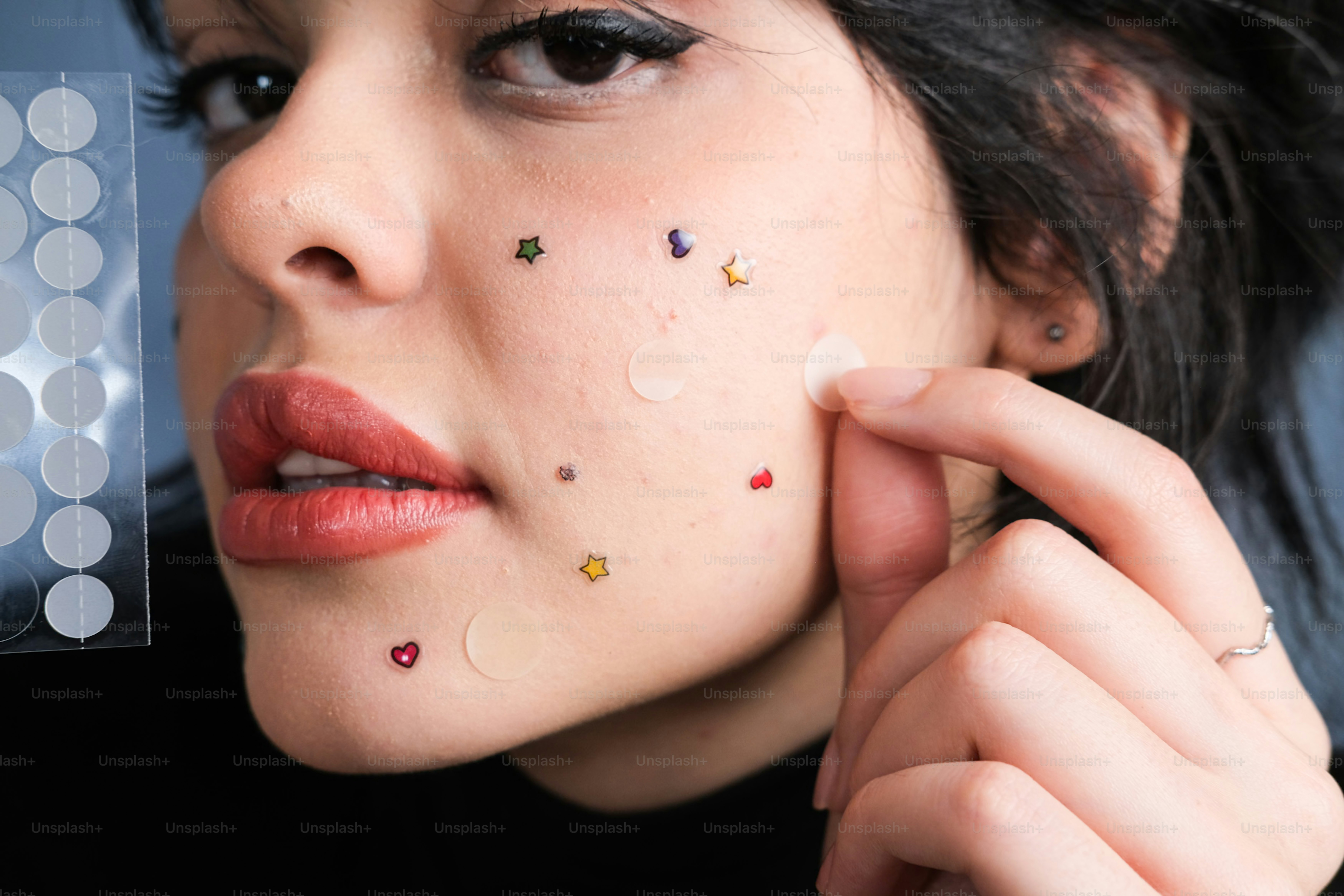 Femme qui applique des patchs décoratifs pour boutons sur son visage.