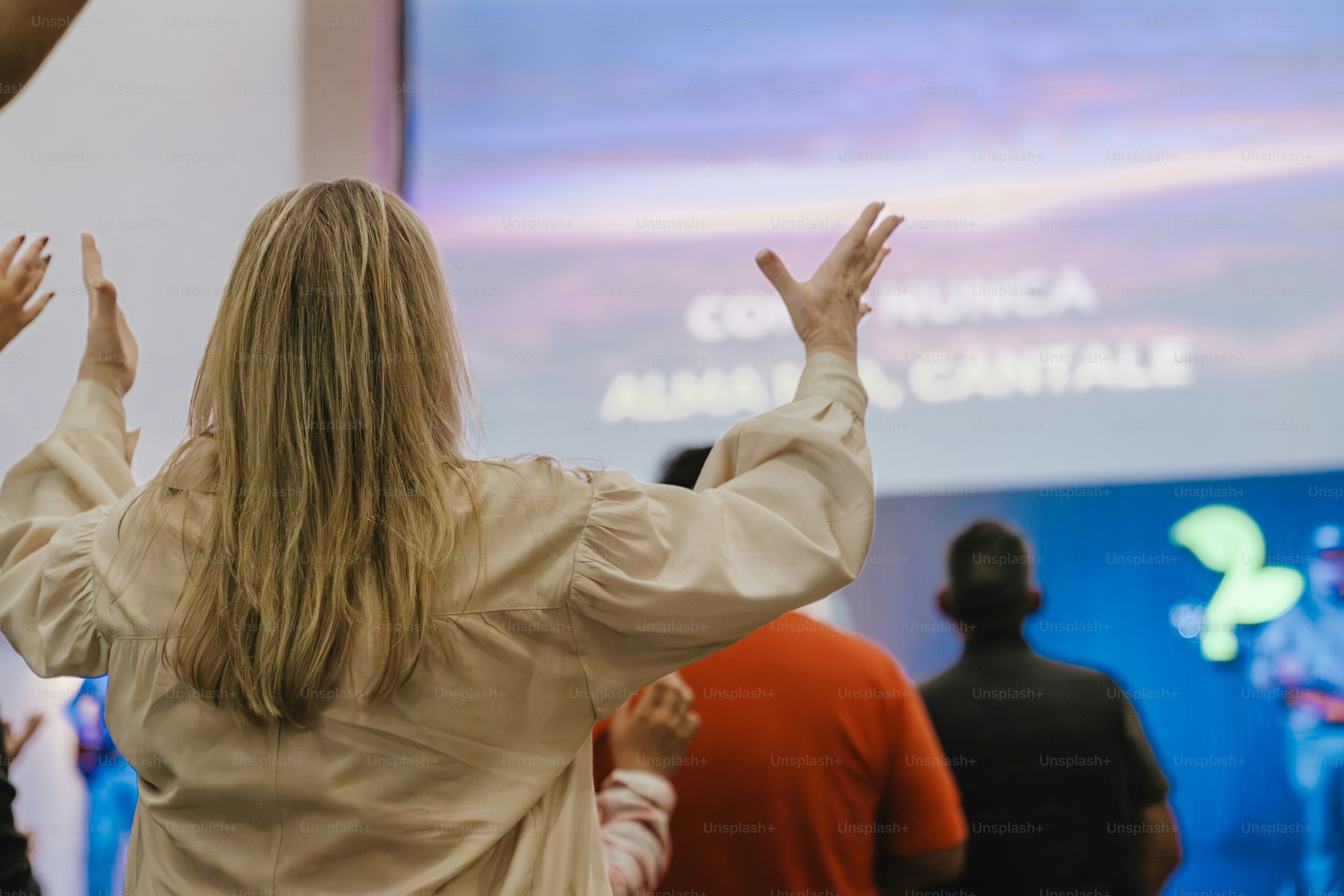 Persone con le mani alzate in preghiera in una chiesa.