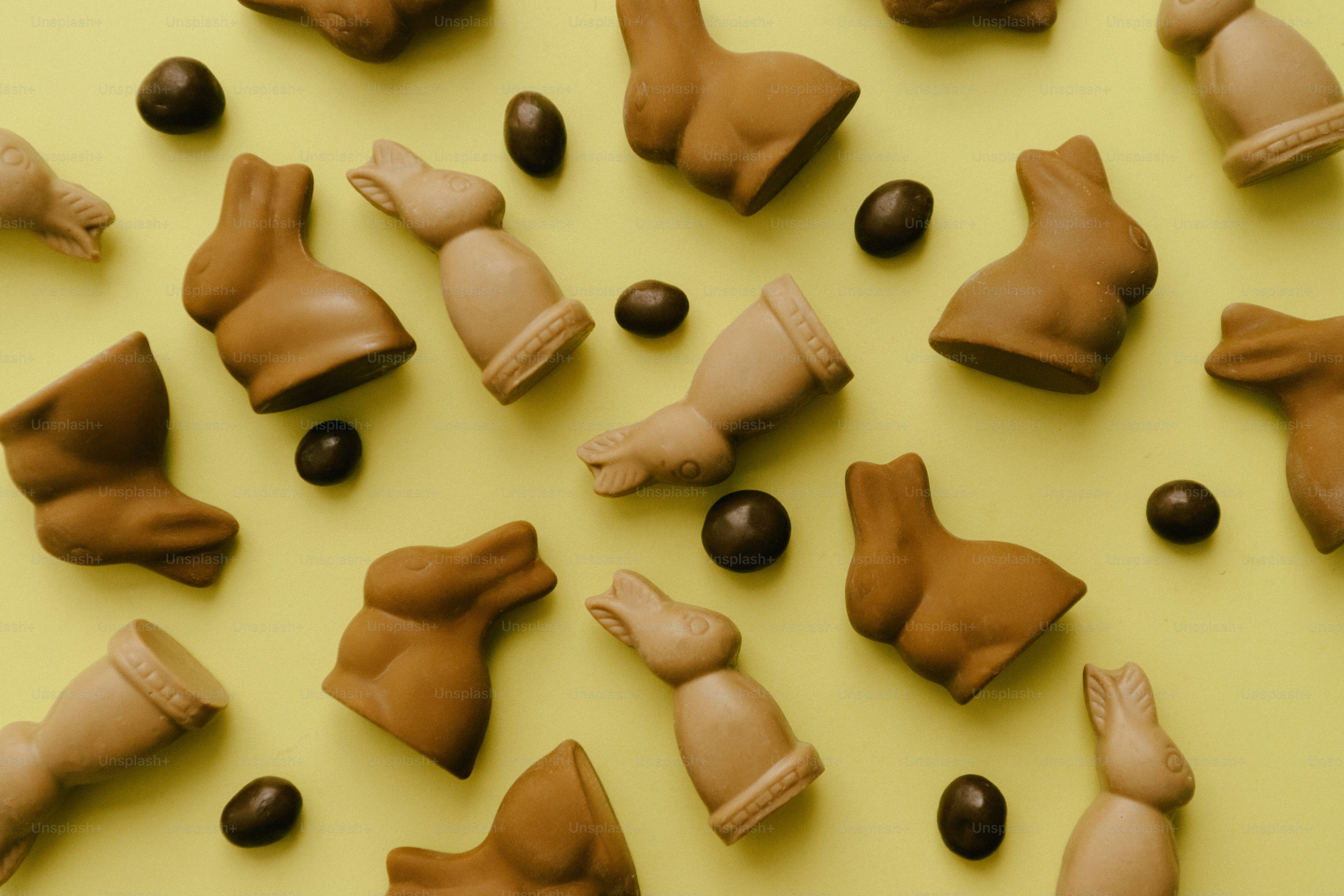 Chocolate bunnies and eggs scattered on yellow background