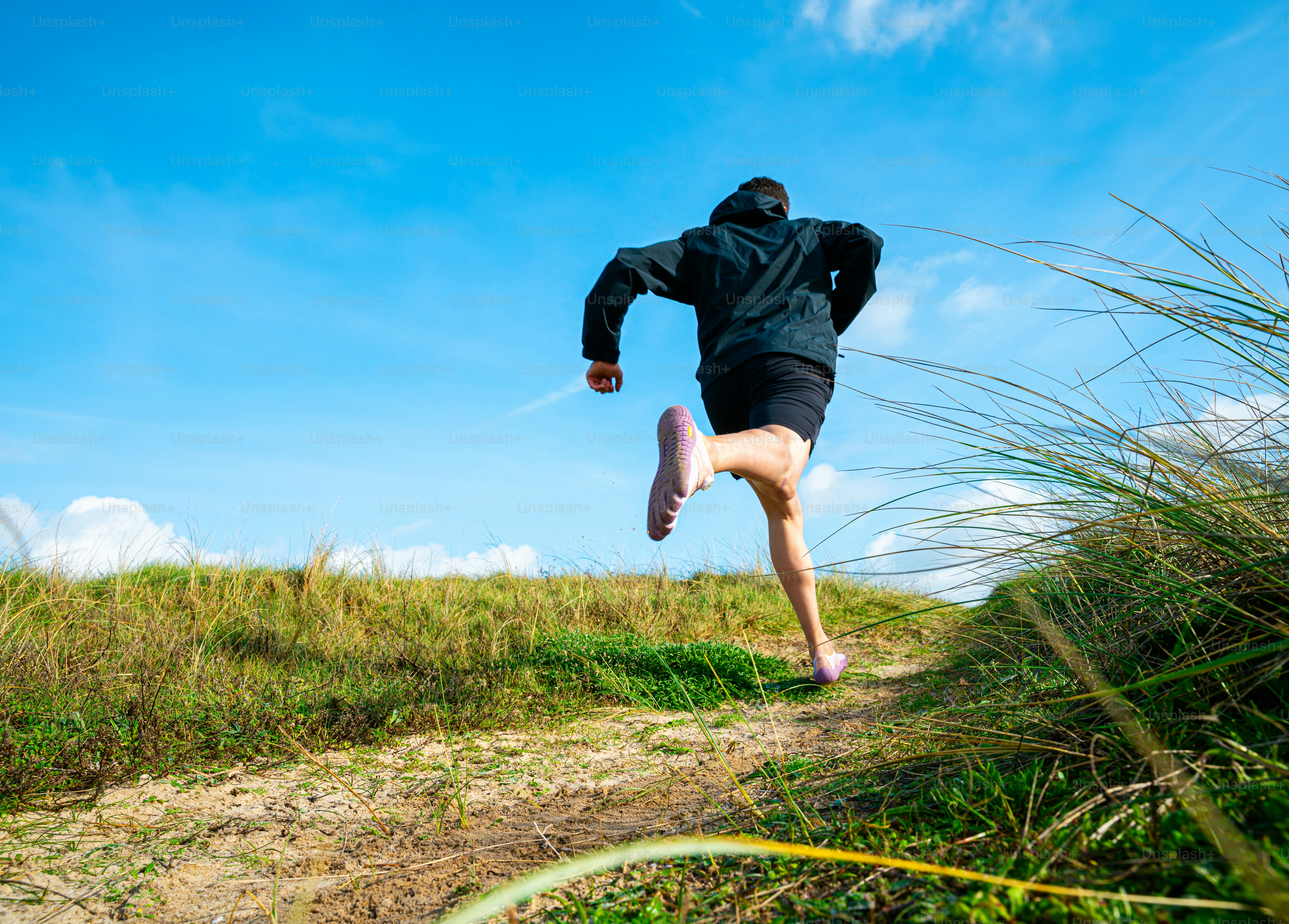 Person running on a grassy path under blue sky photo – Fitness Image on ...