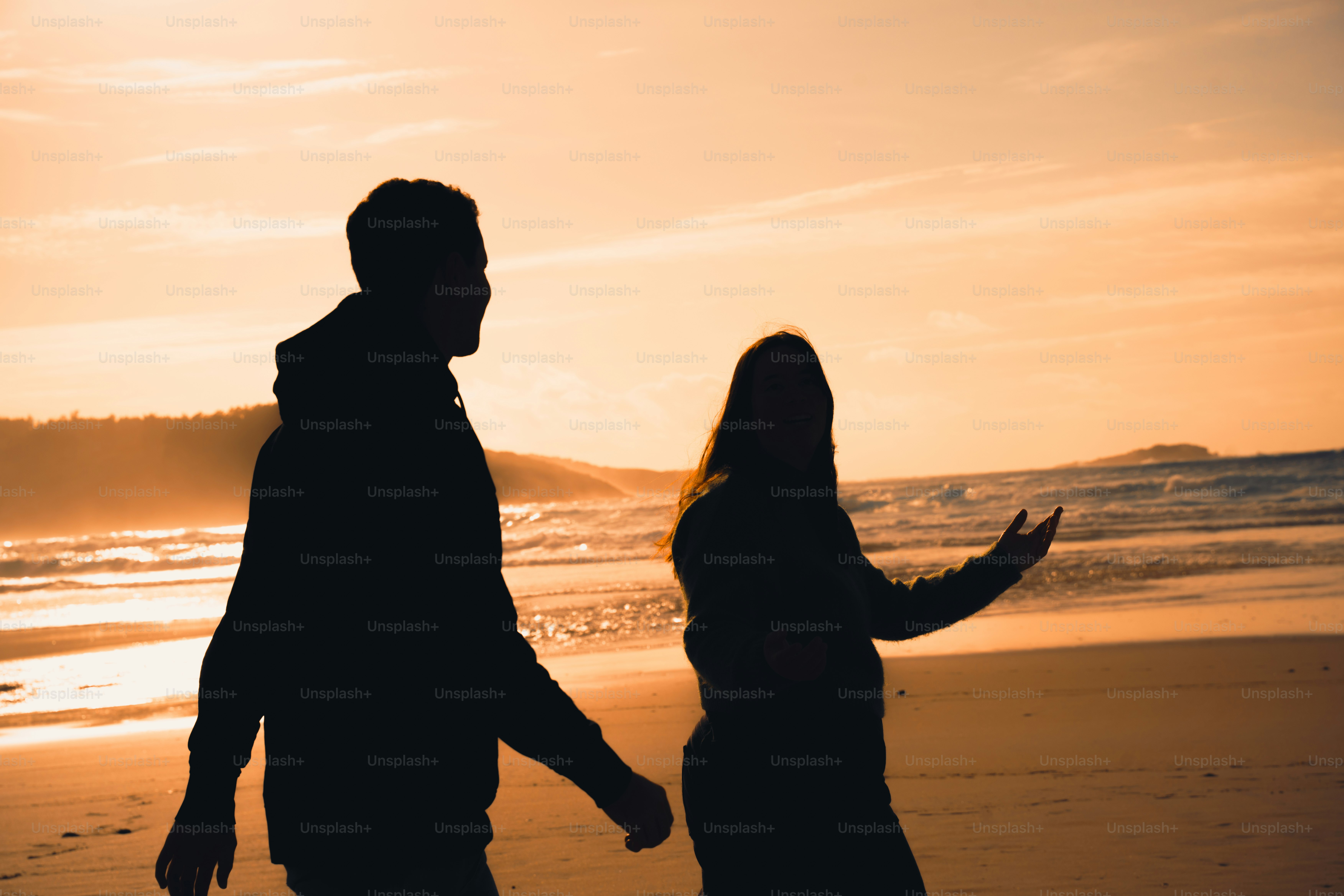 Couple walking on beach at sunset