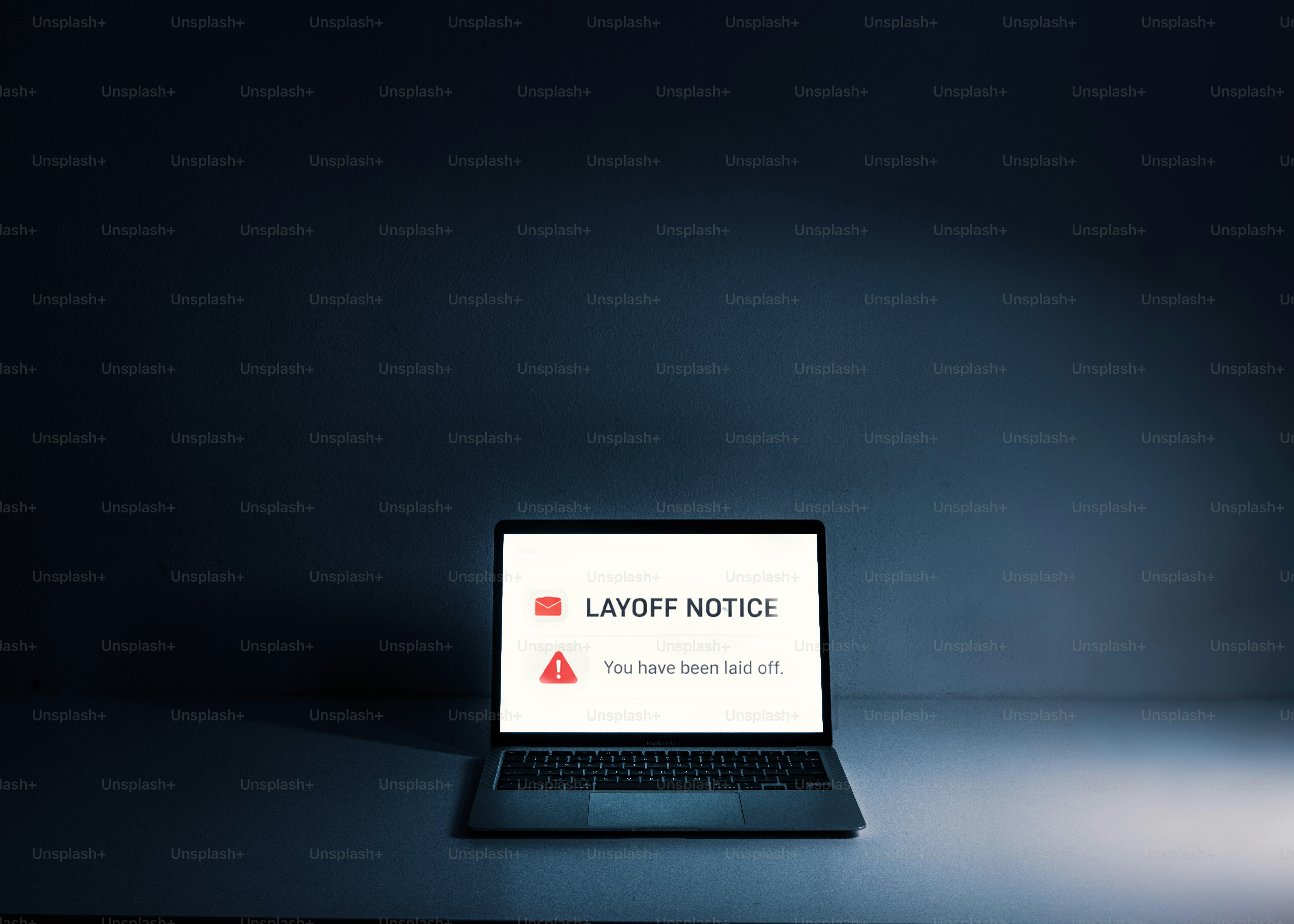 Laptop displaying a layoff notice on screen.