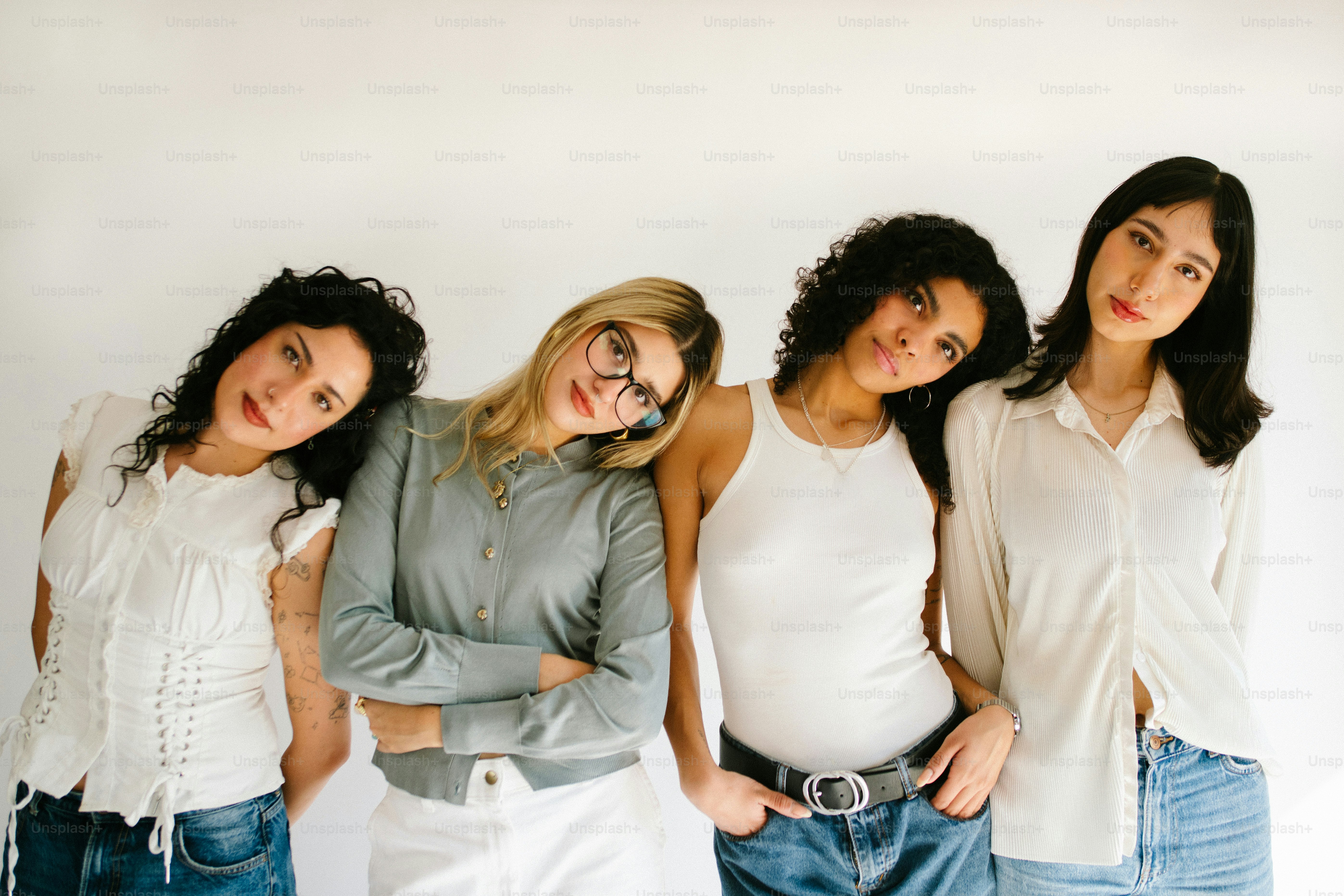 Quattro giovani donne che appoggiano le teste insieme su uno sfondo bianco