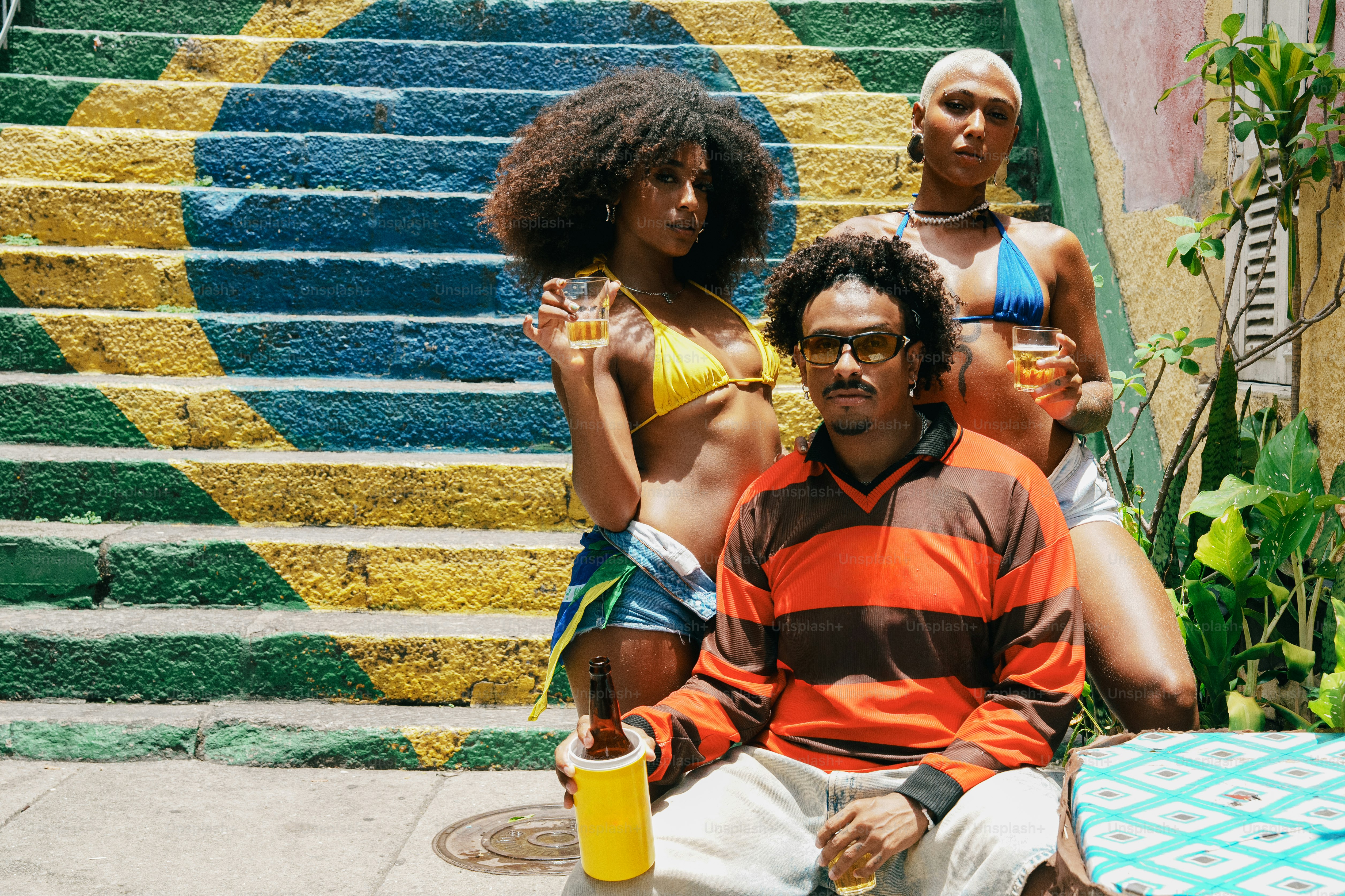 Tre persone che posano davanti alle scale con la bandiera brasiliana