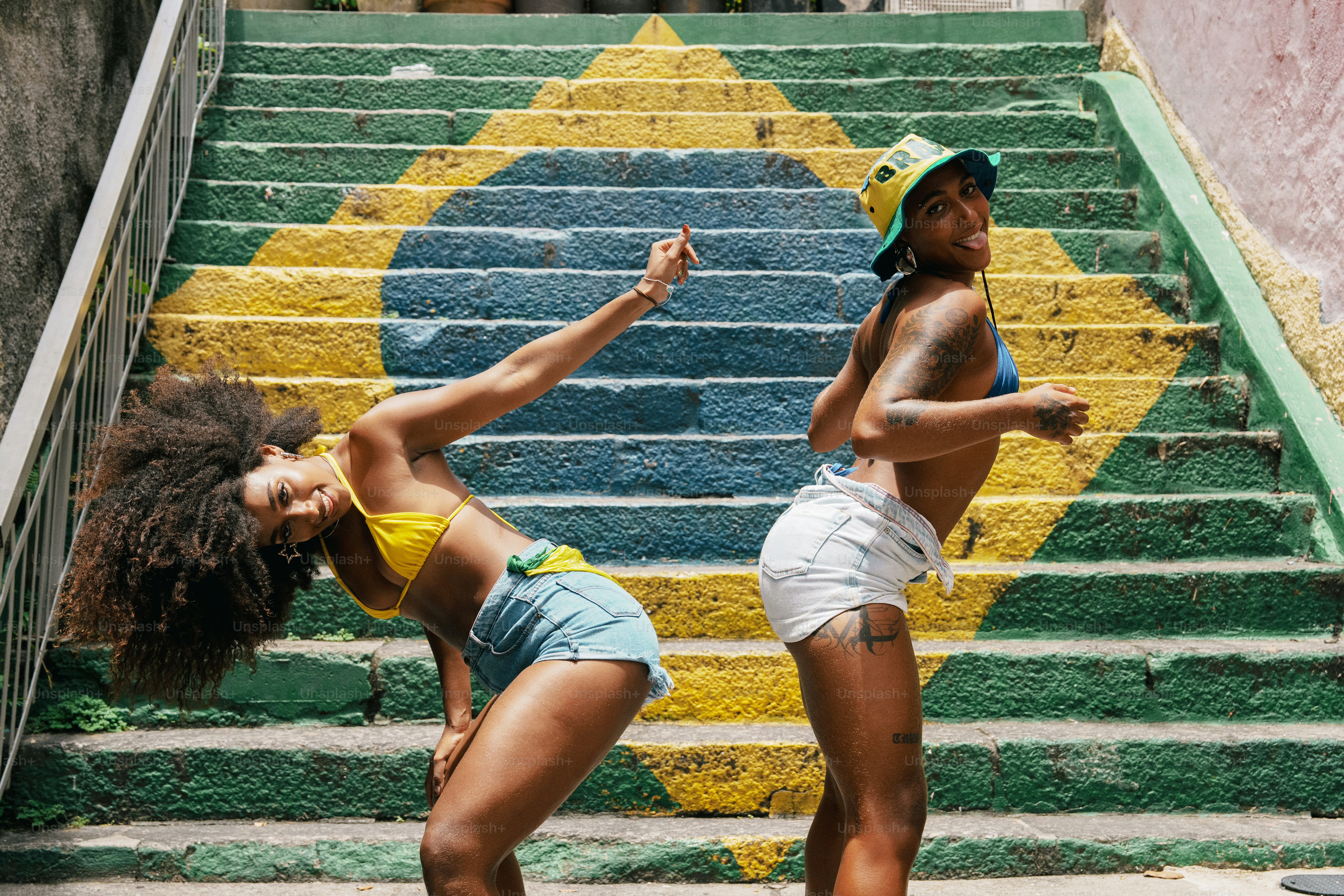 Zwei Frauen, die auf Treppen tanzen, die mit der brasilianischen Flagge bemalt sind.