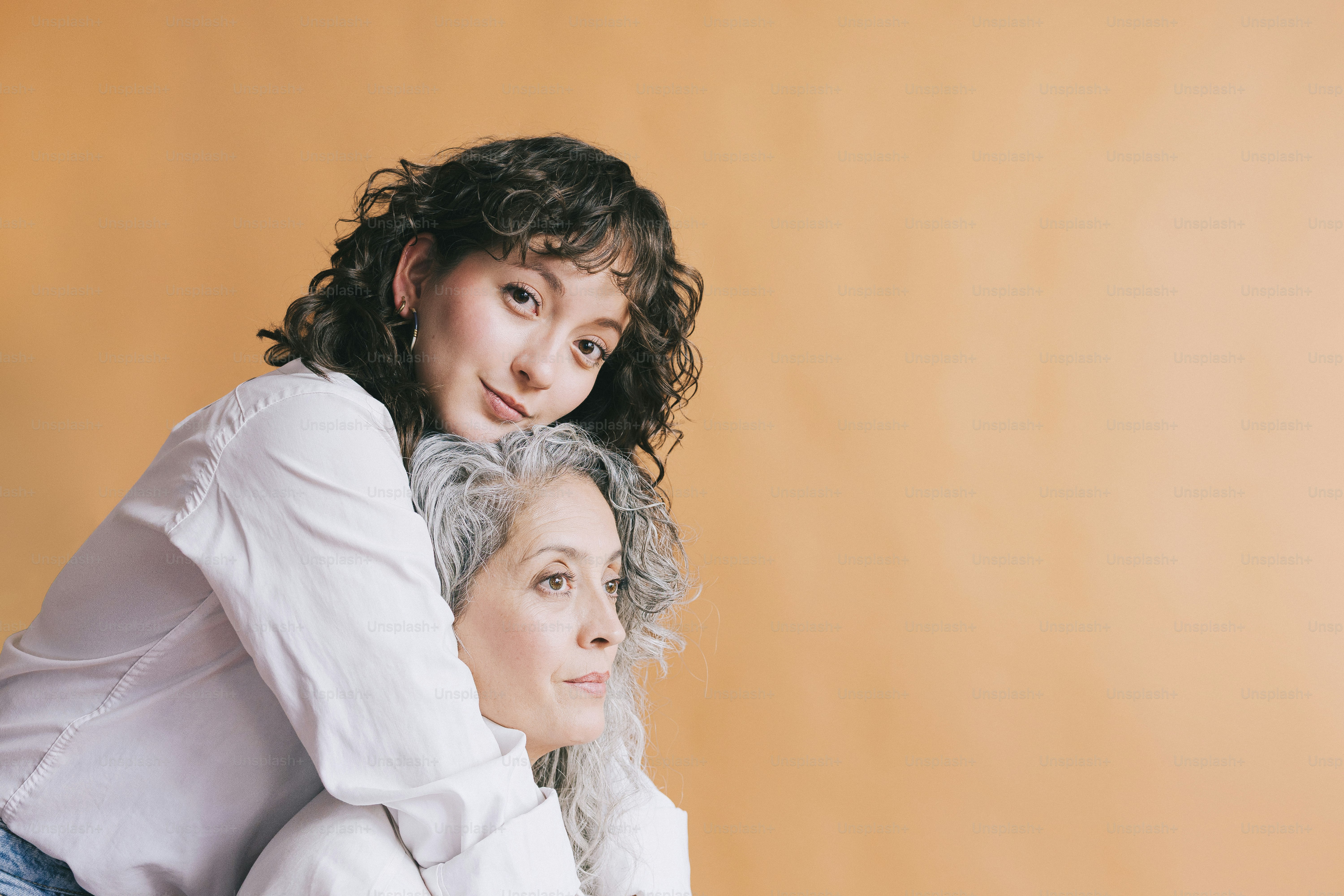 Young woman hugs older woman from behind