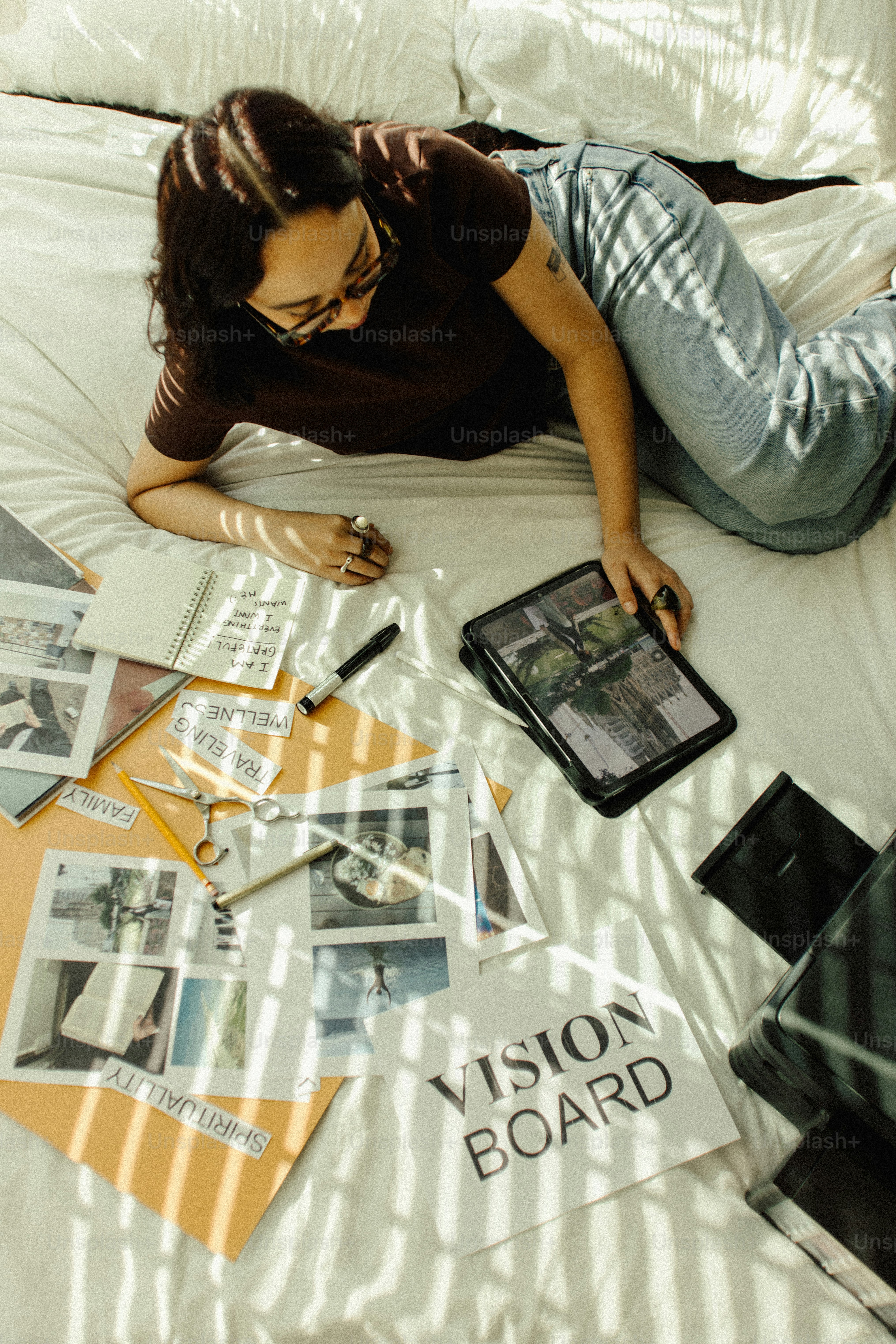 Woman creating a vision board on a bed.