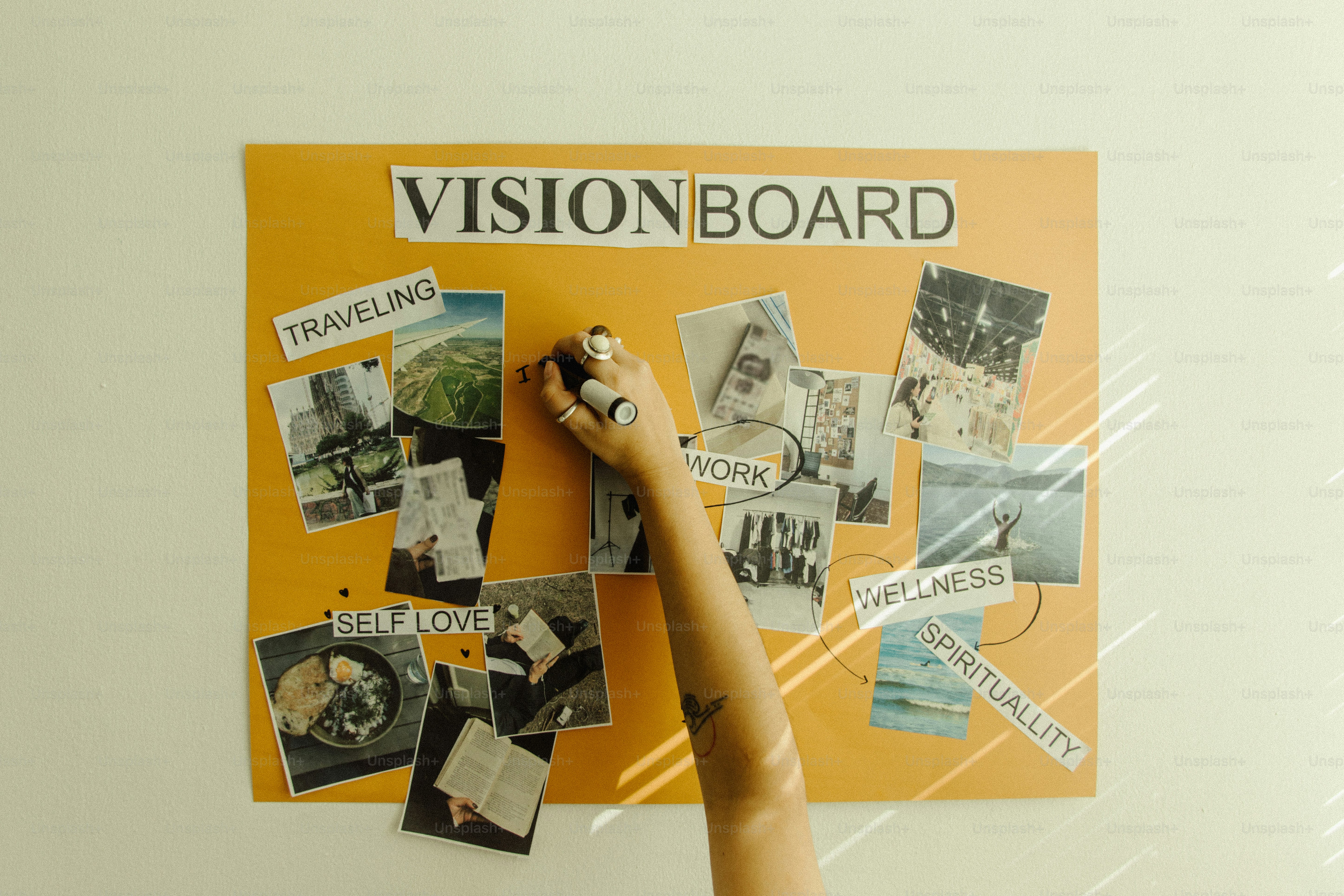 A hand adding photos to a vision board.