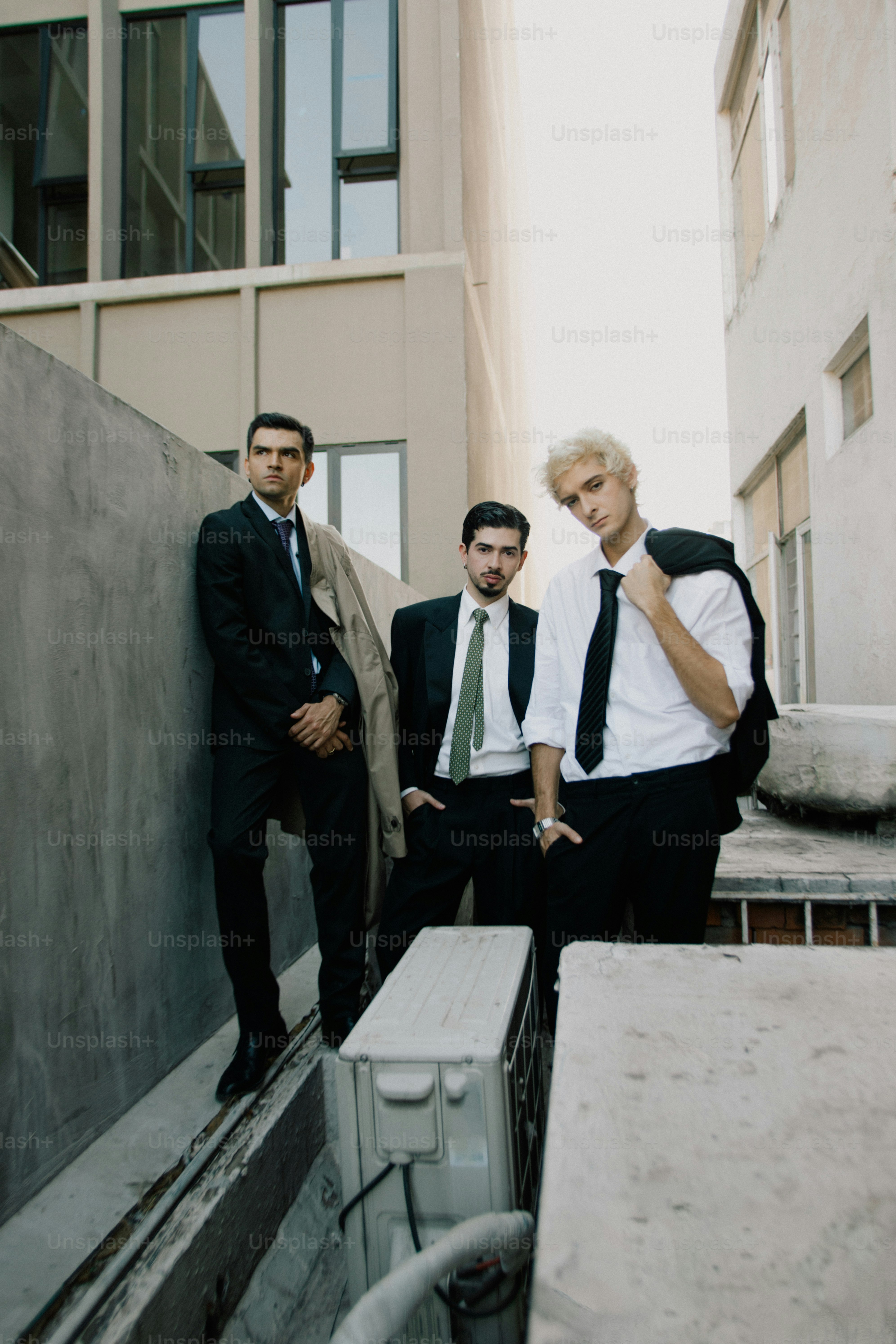 Three men in suits standing in an alleyway
