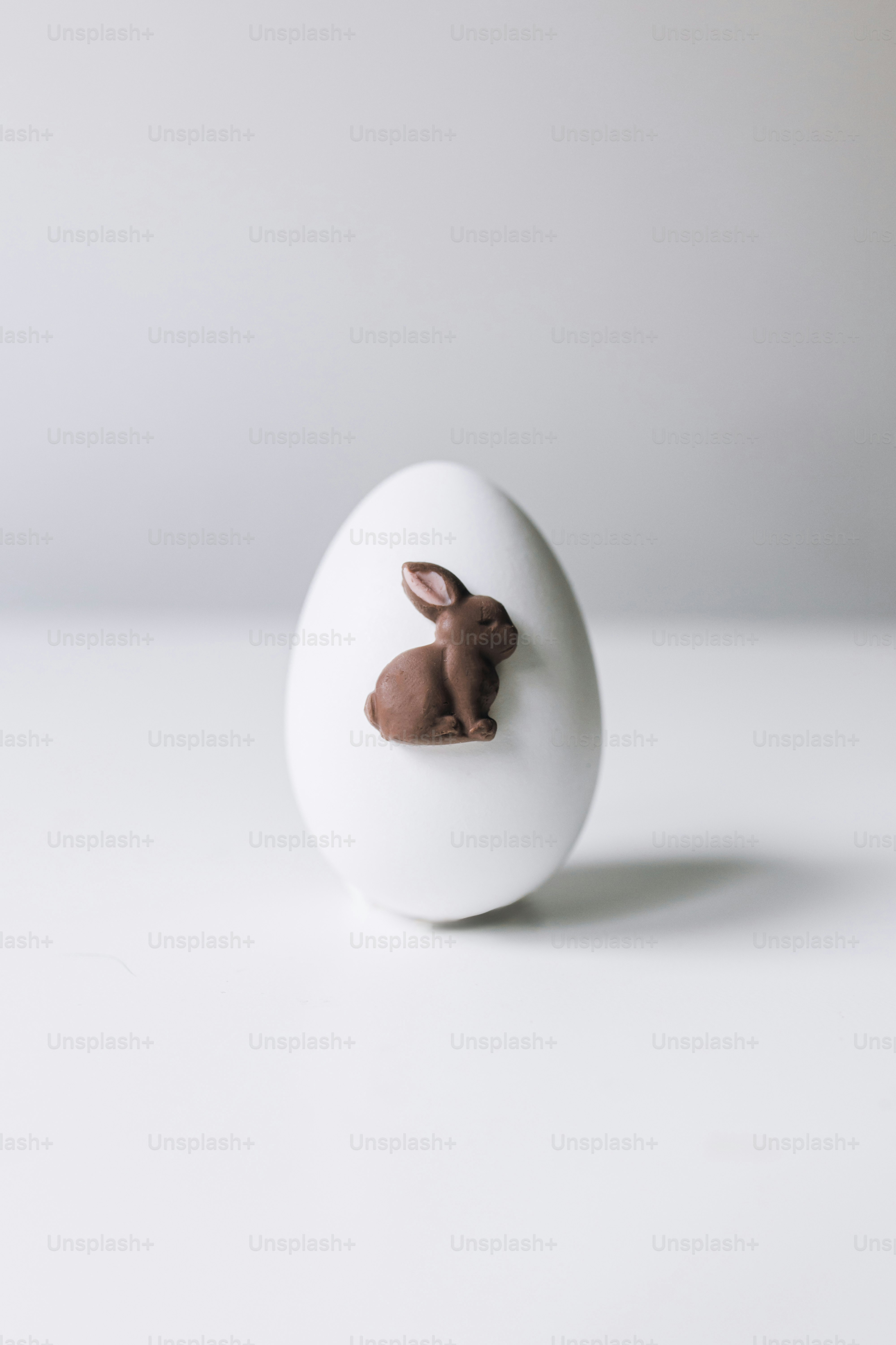 Un uovo bianco con una decorazione a forma di coniglietto di cioccolato