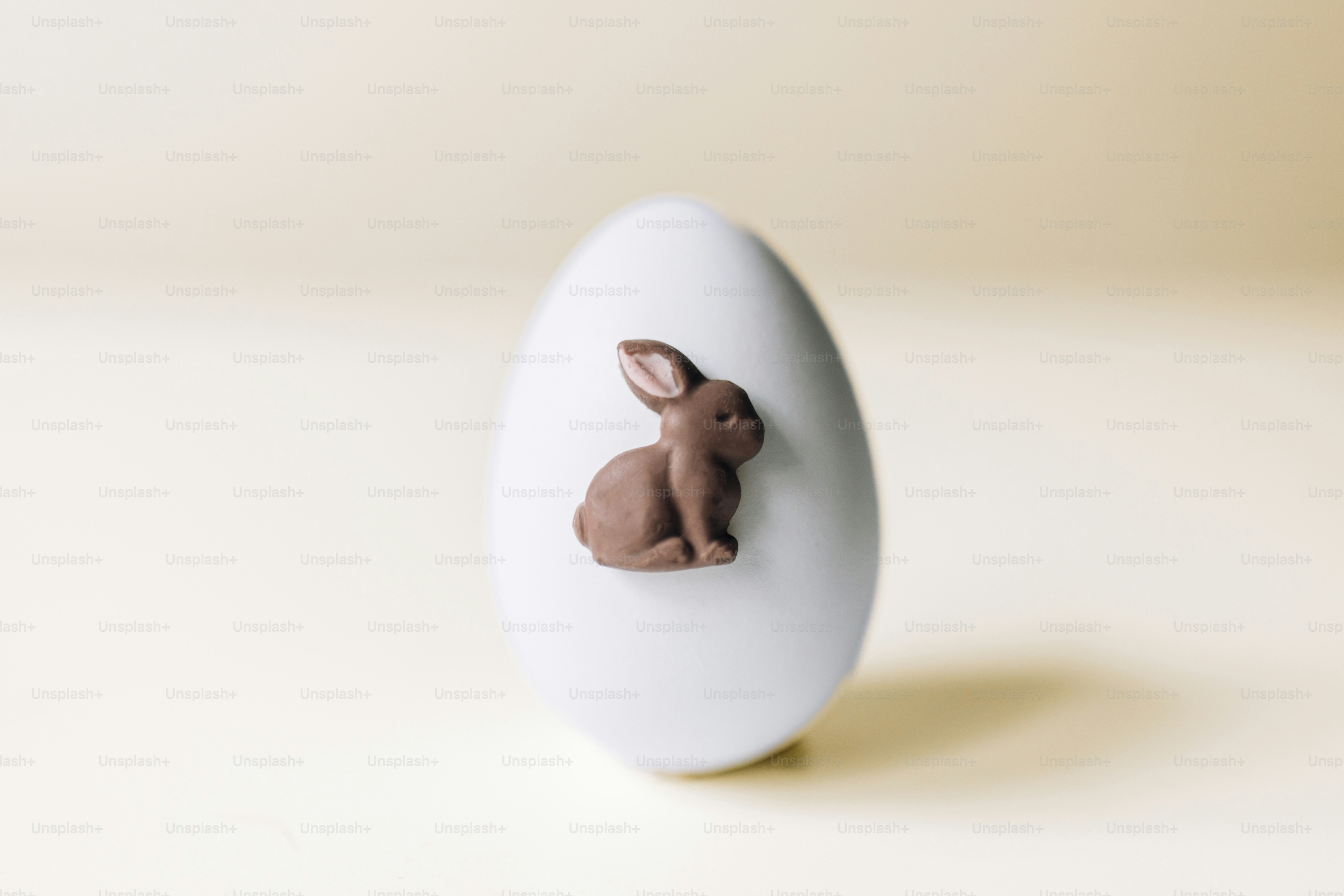 Un uovo bianco con una decorazione a forma di coniglietto di cioccolato.