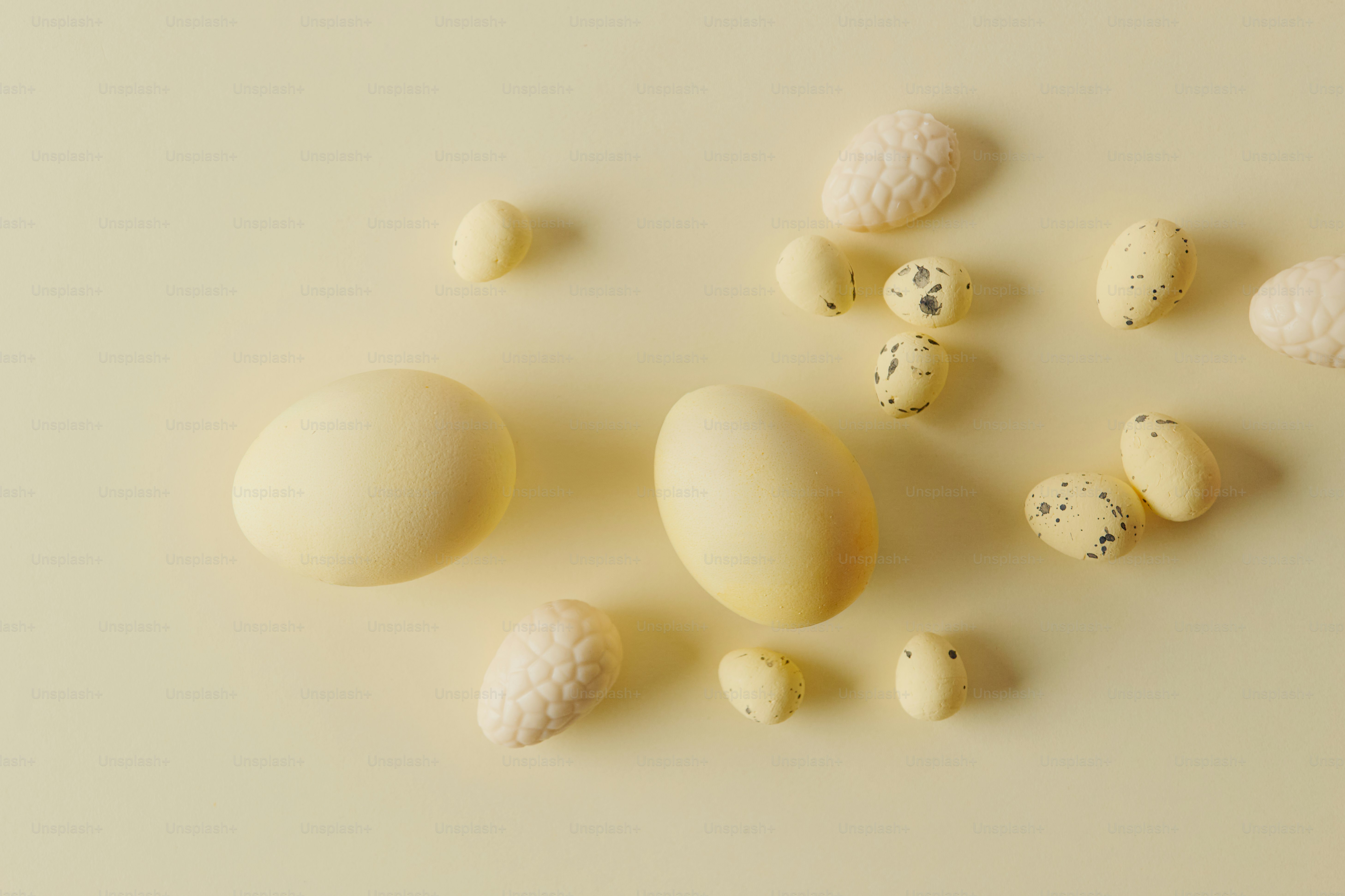 Various sizes of light colored eggs on a cream background