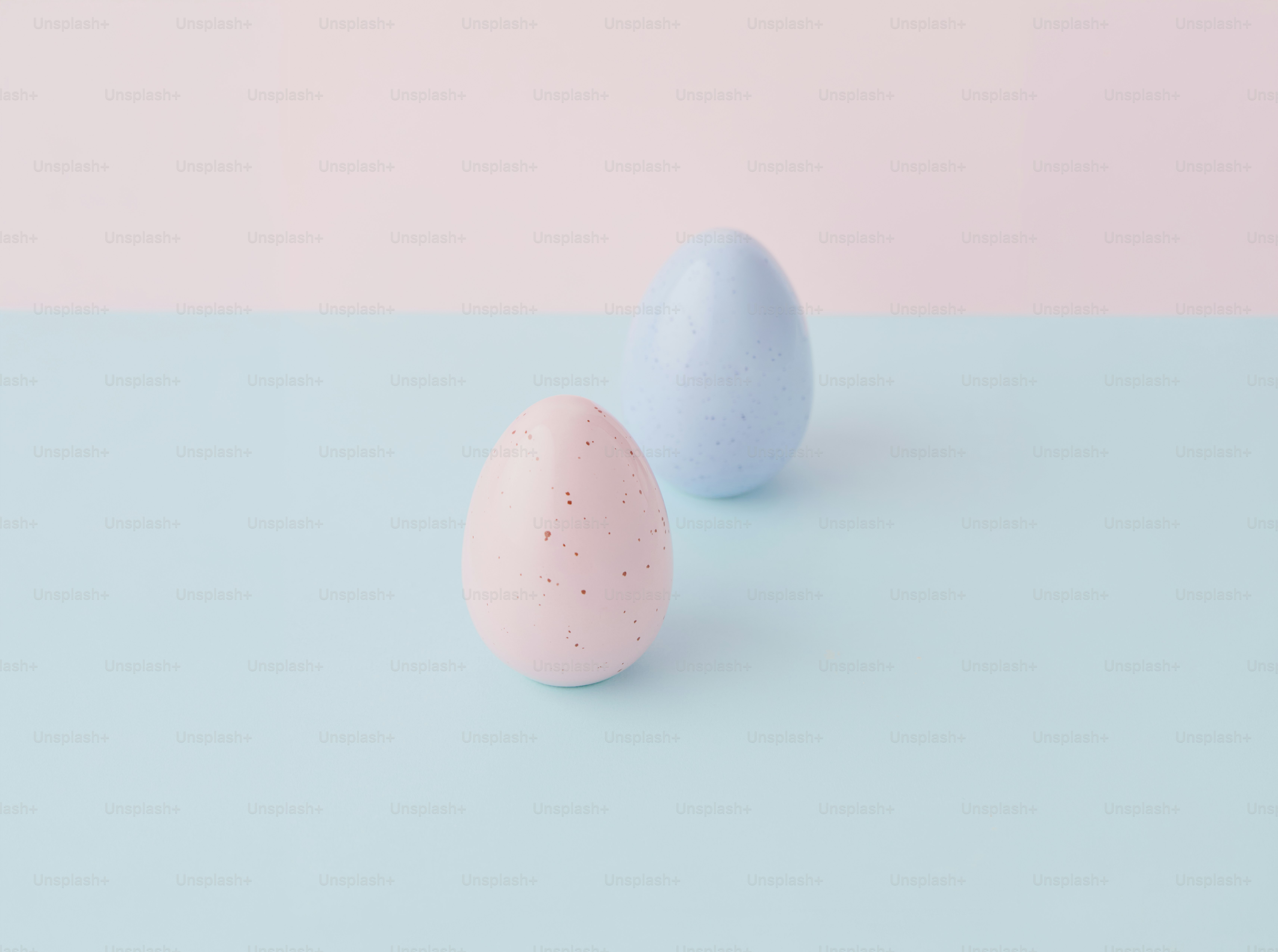 Dua telur paskah pastel di permukaan biru.