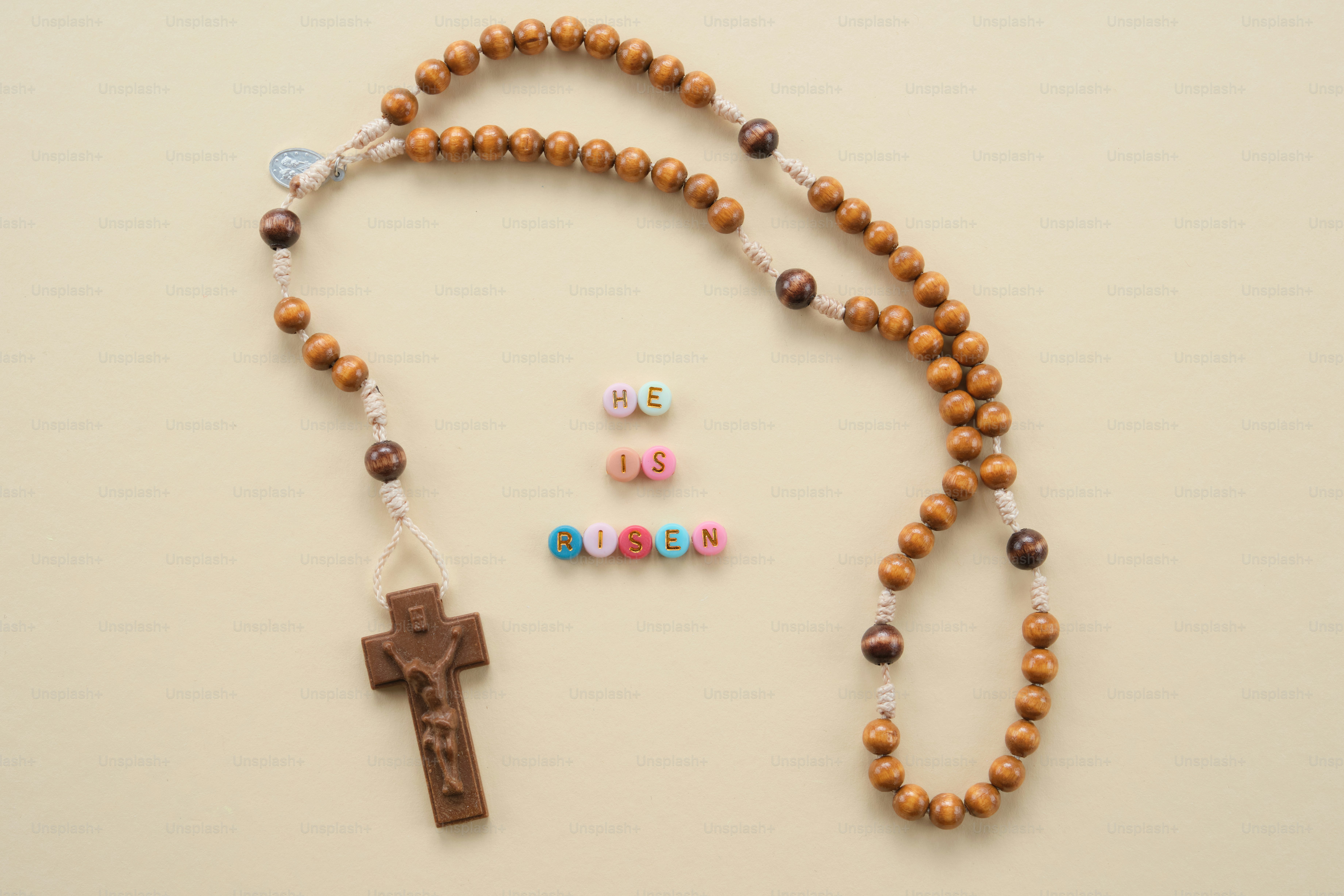 Rosary beads and colorful alphabet beads spelling 'jesus'.