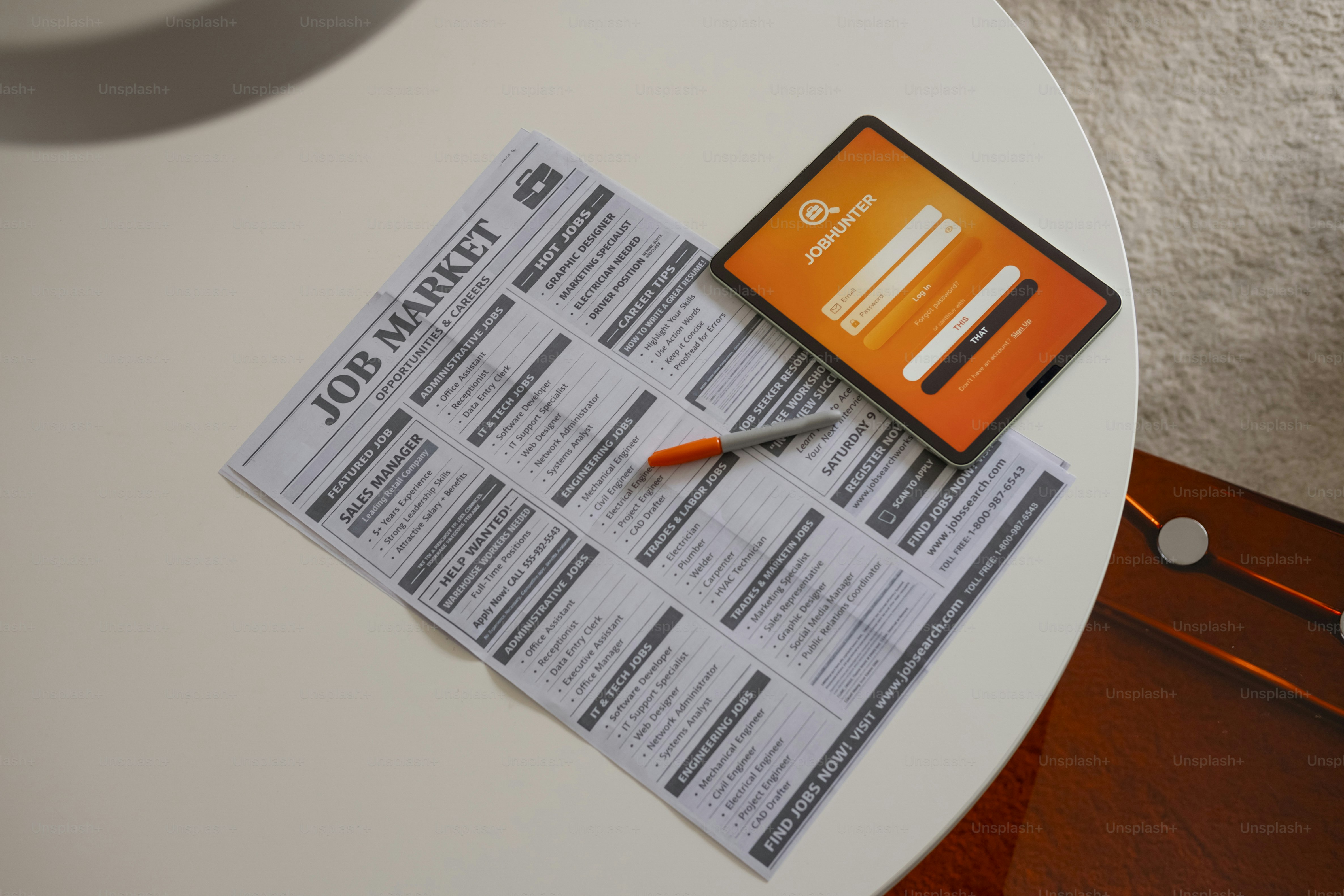 Job market newspaper and tablet on white table.