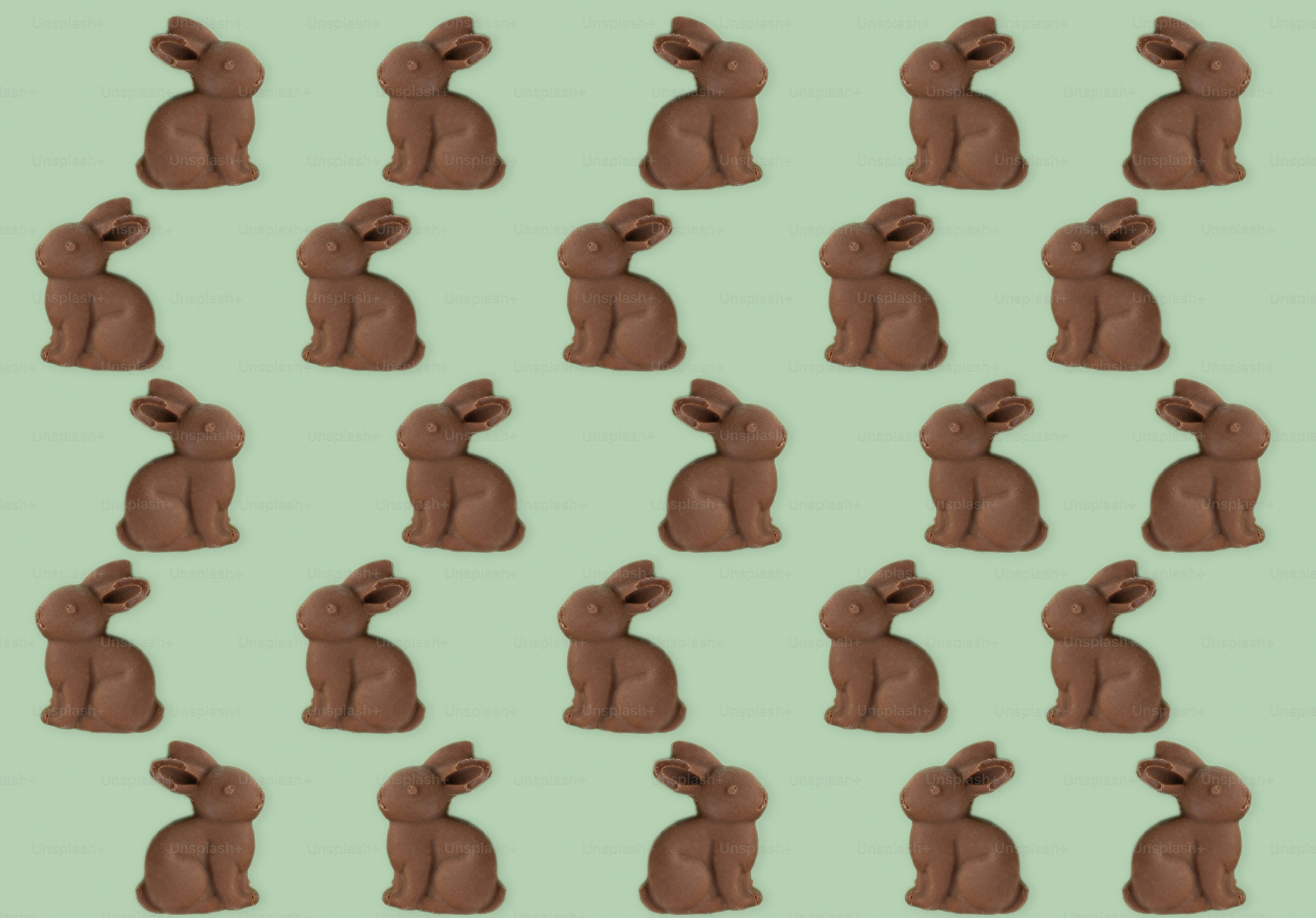 Many small chocolate bunnies arranged on a green background
