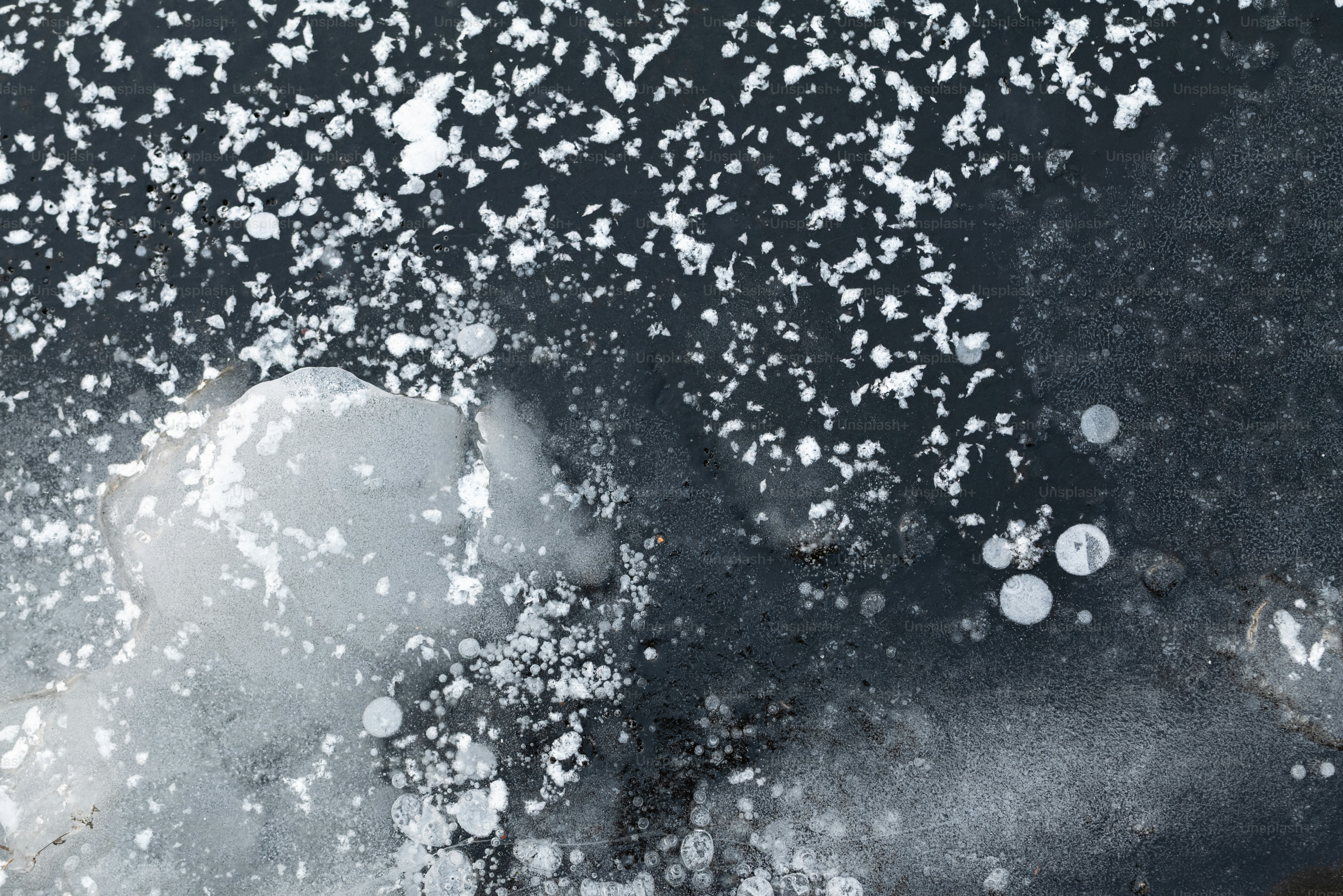 Bubbles frozen in dark ice with white snow