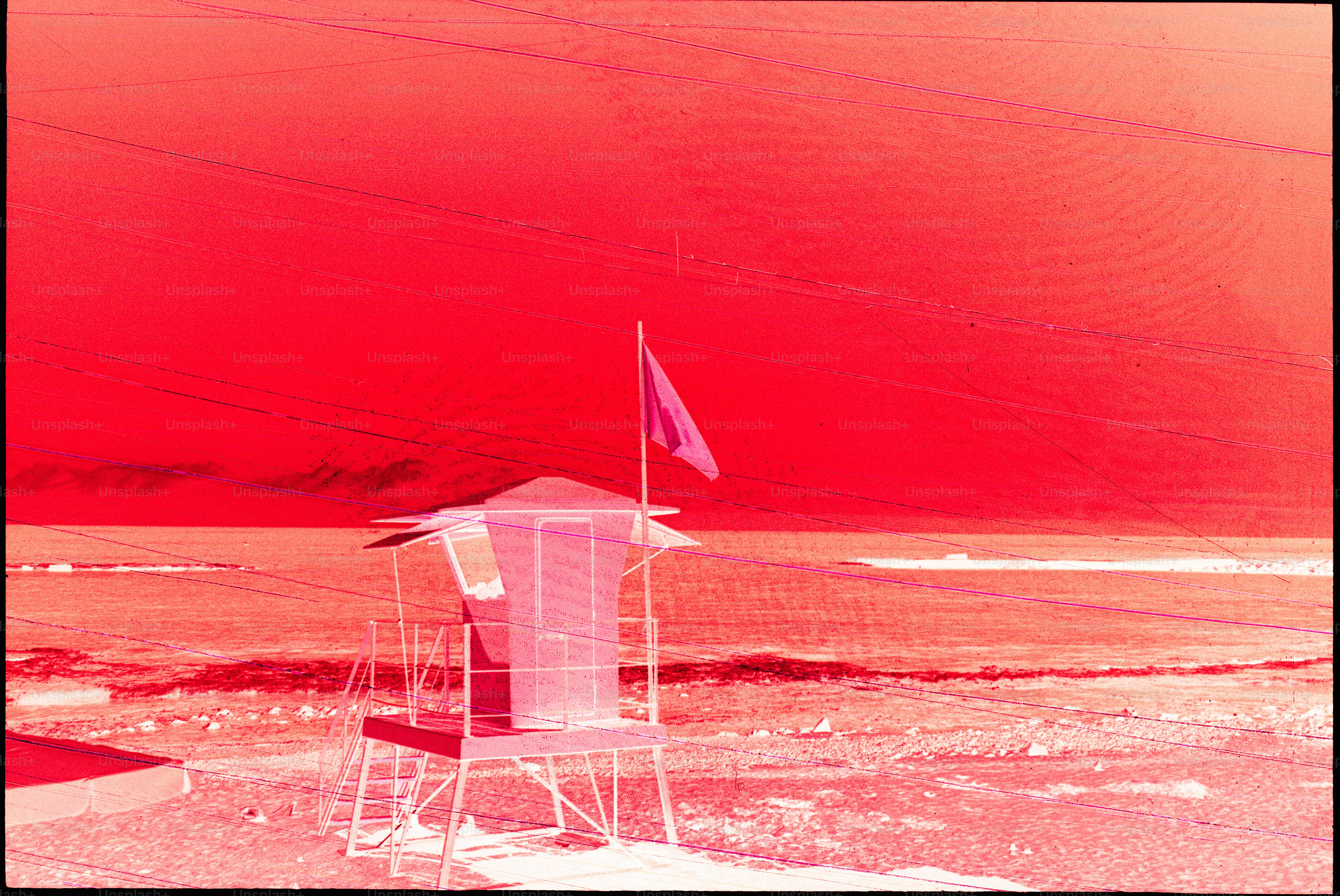 Torre de socorrismo en una playa bajo un cielo rojo
