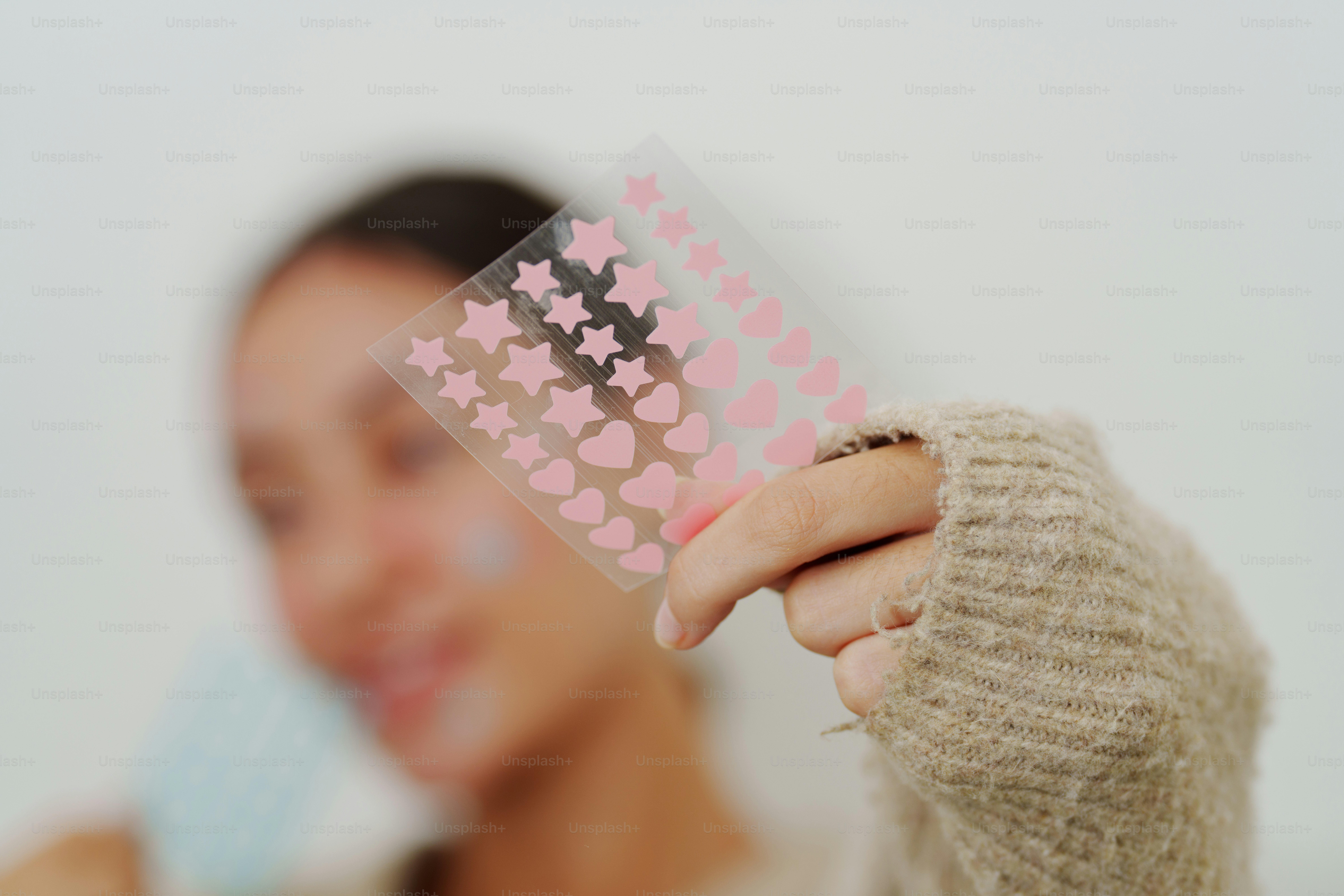 Frau hält ein Blatt mit rosa Herzen und Sternaufklebern