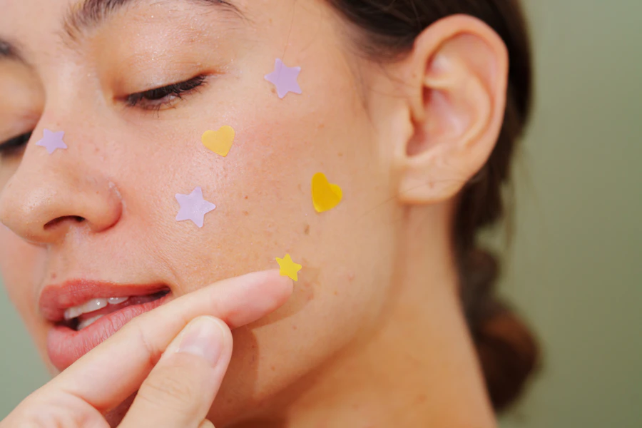 Woman applying colorful star and heart shaped pimple patches