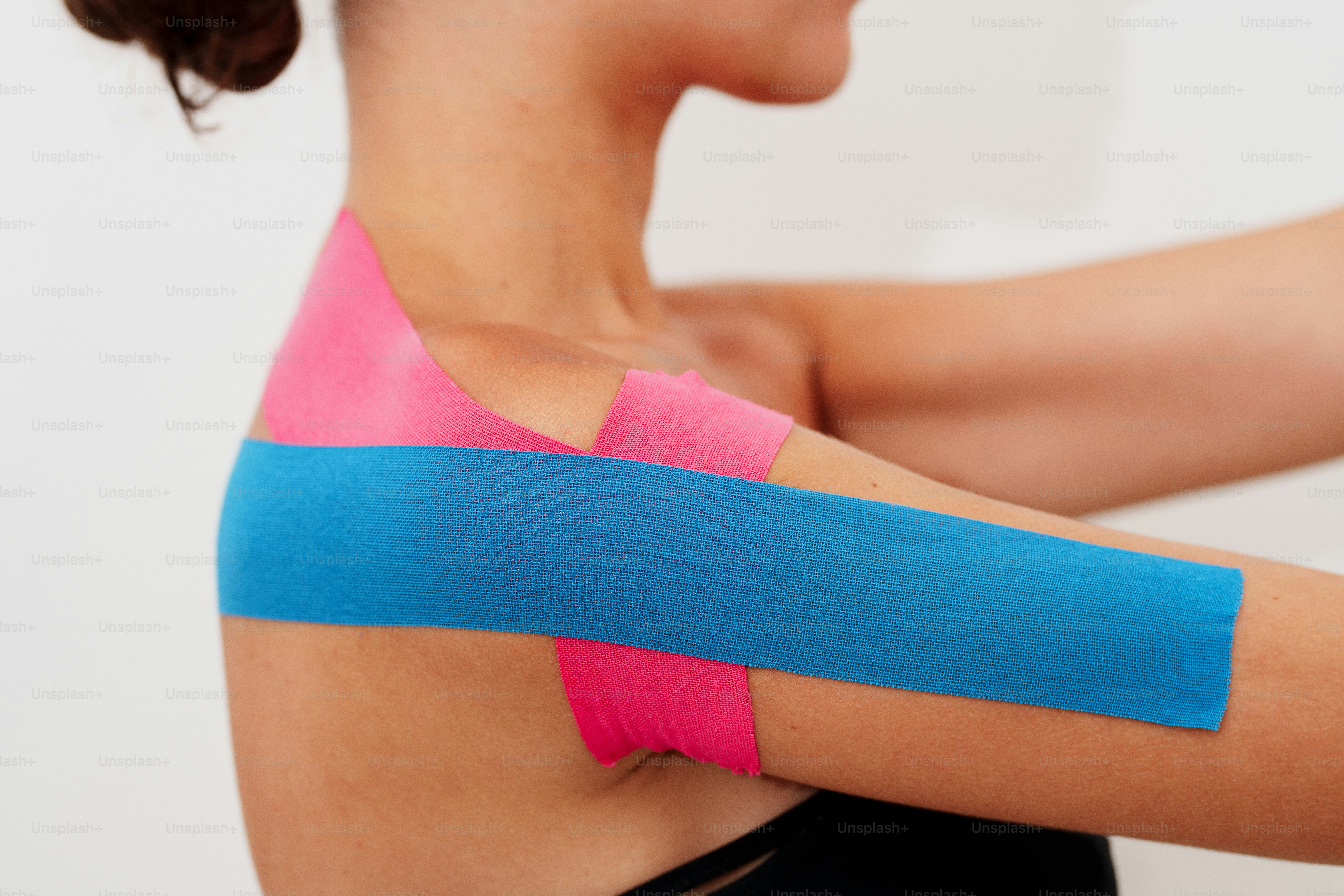 Person mit blauem und pinkem Sportklebeband am Arm