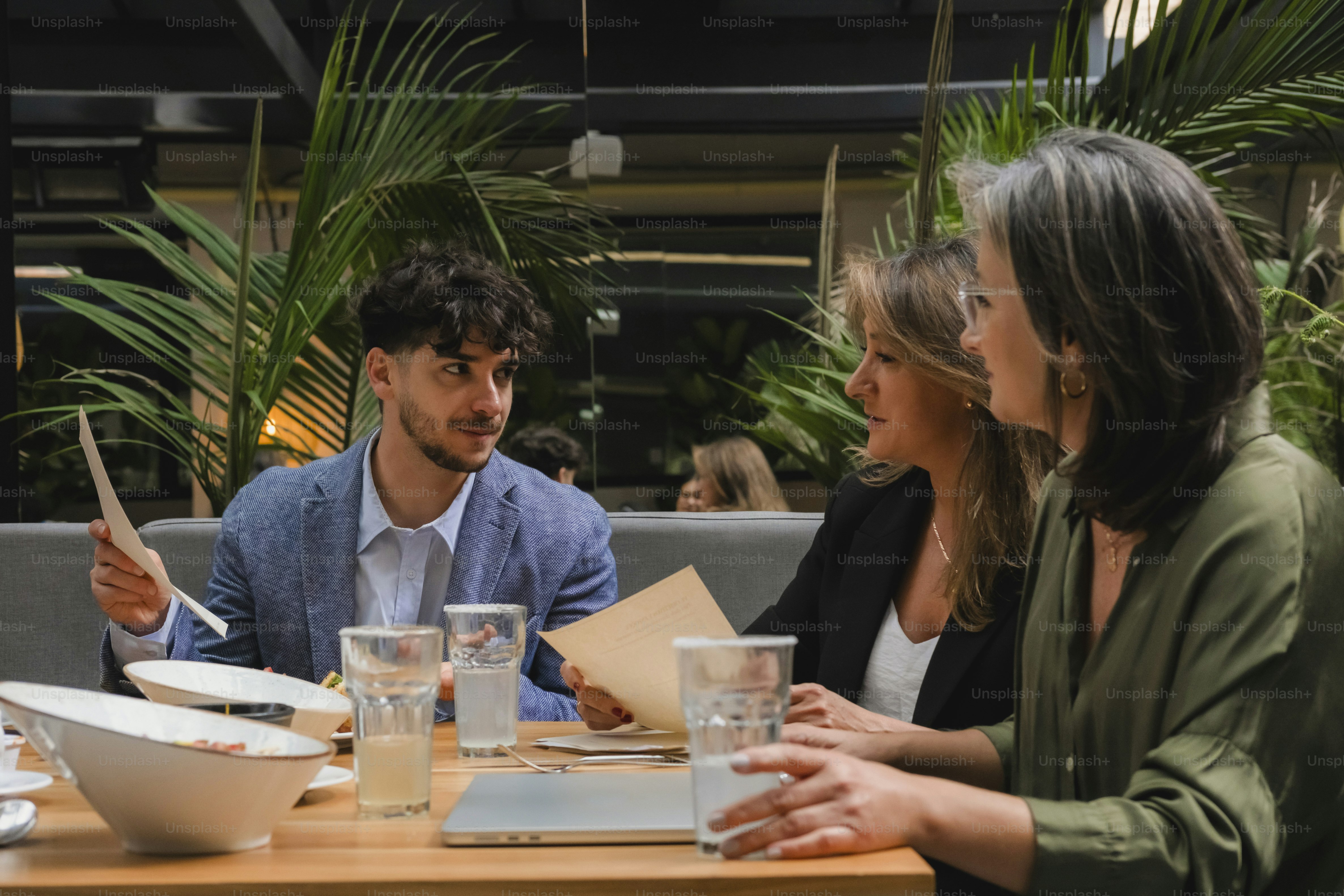 Three people talking at a table with drinks.