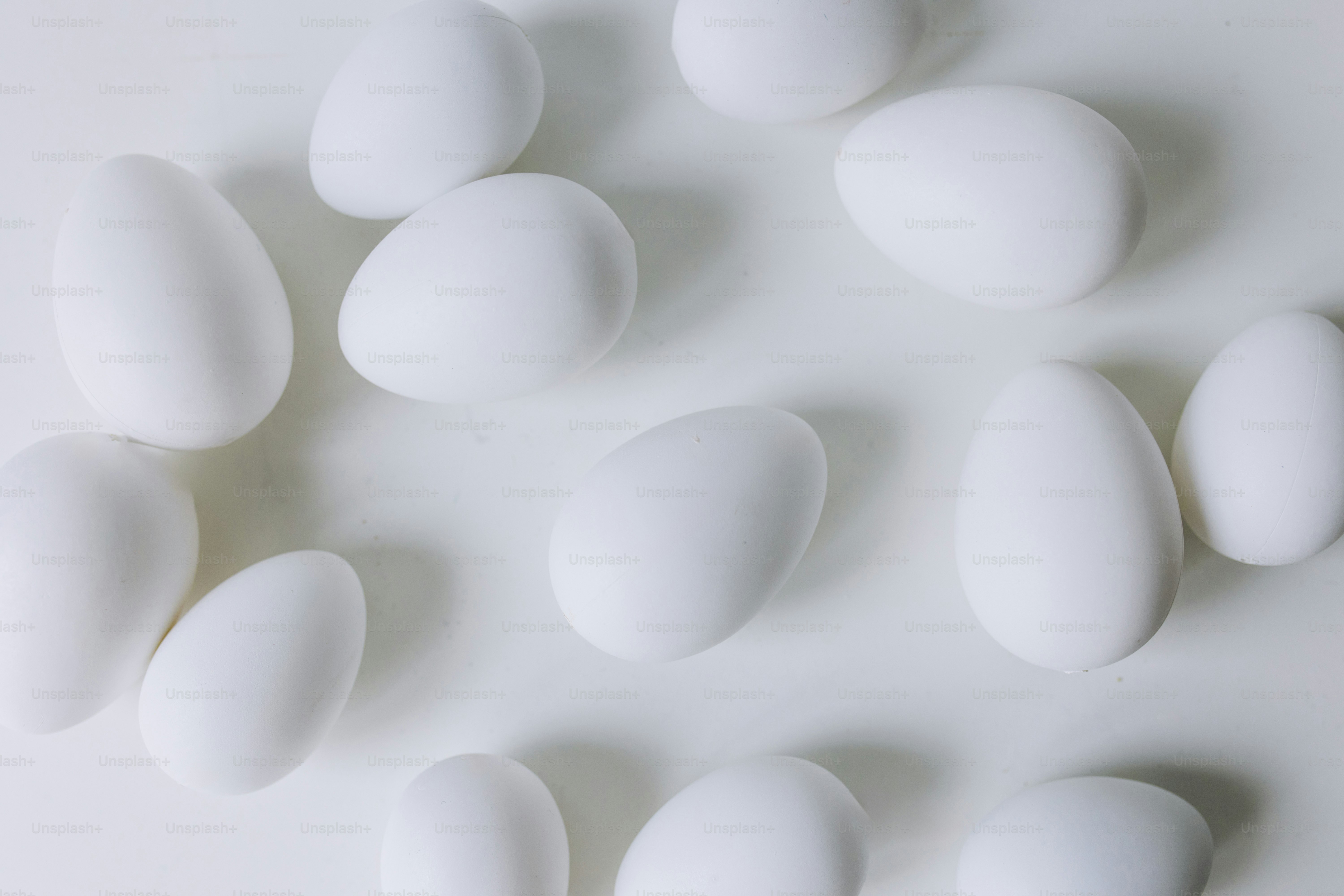 Diverse uova bianche sparse su una superficie bianca