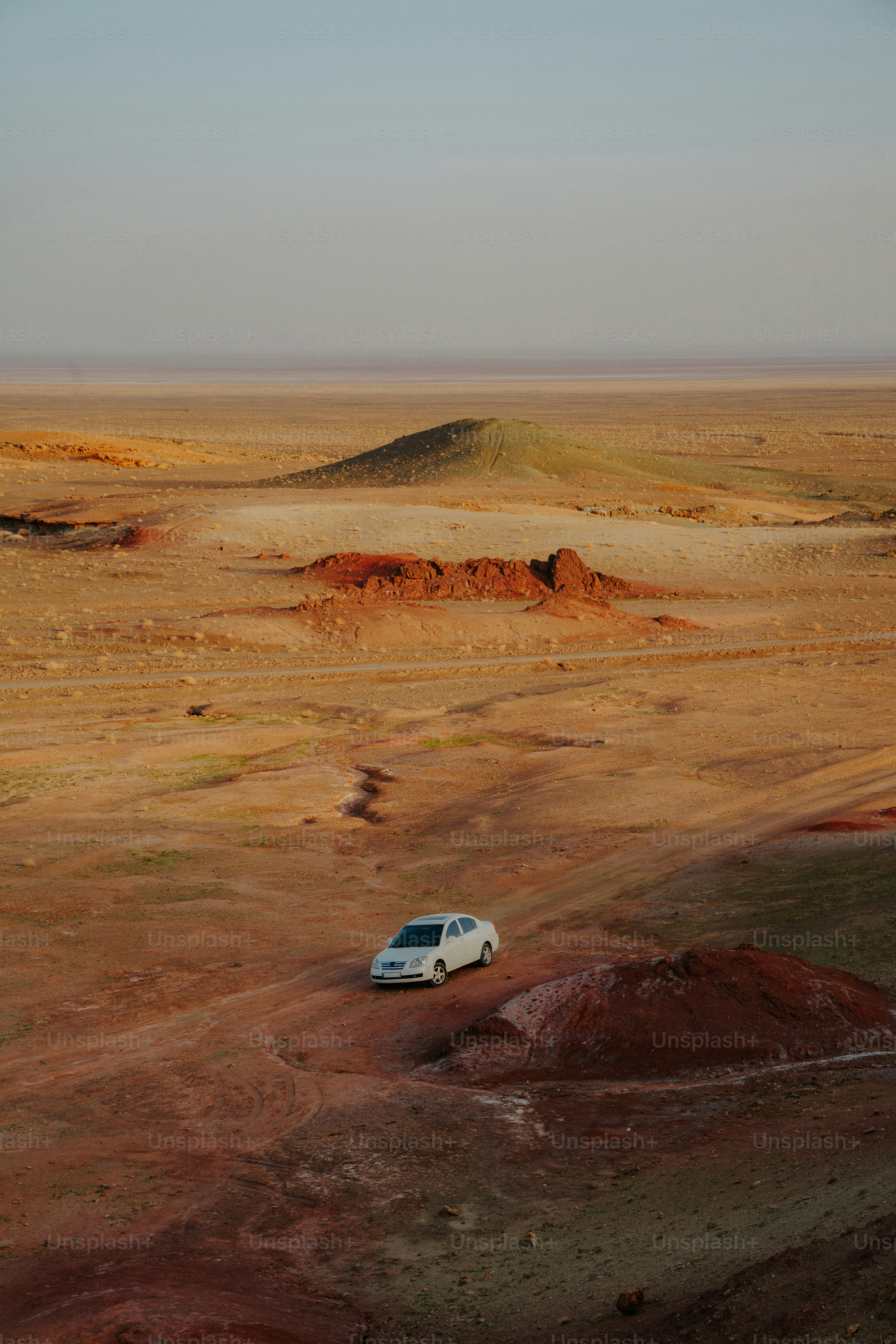 Une voiture solitaire traverse un vaste paysage désertique aride.