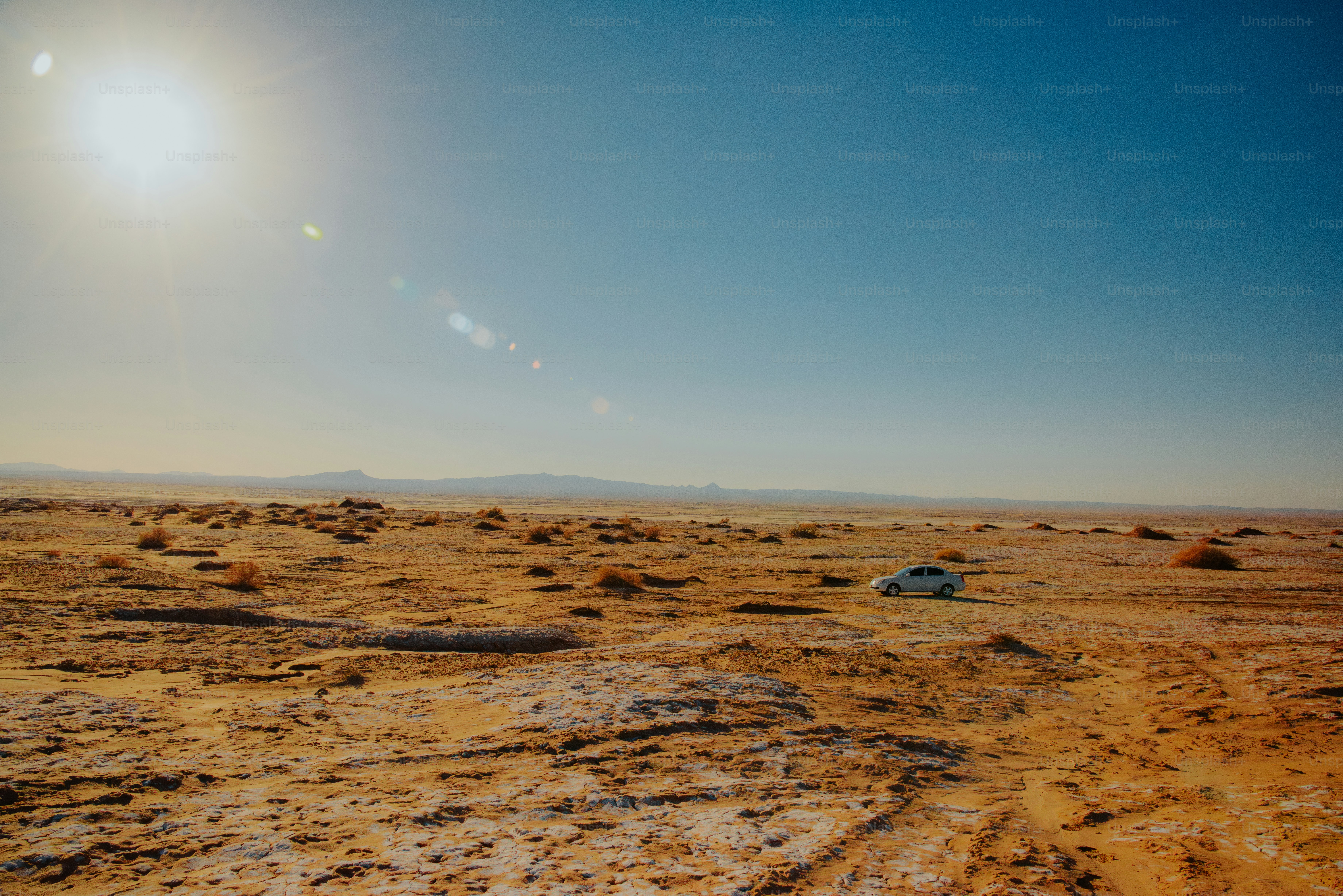 Une voiture solitaire garée dans un vaste paysage désertique aride.