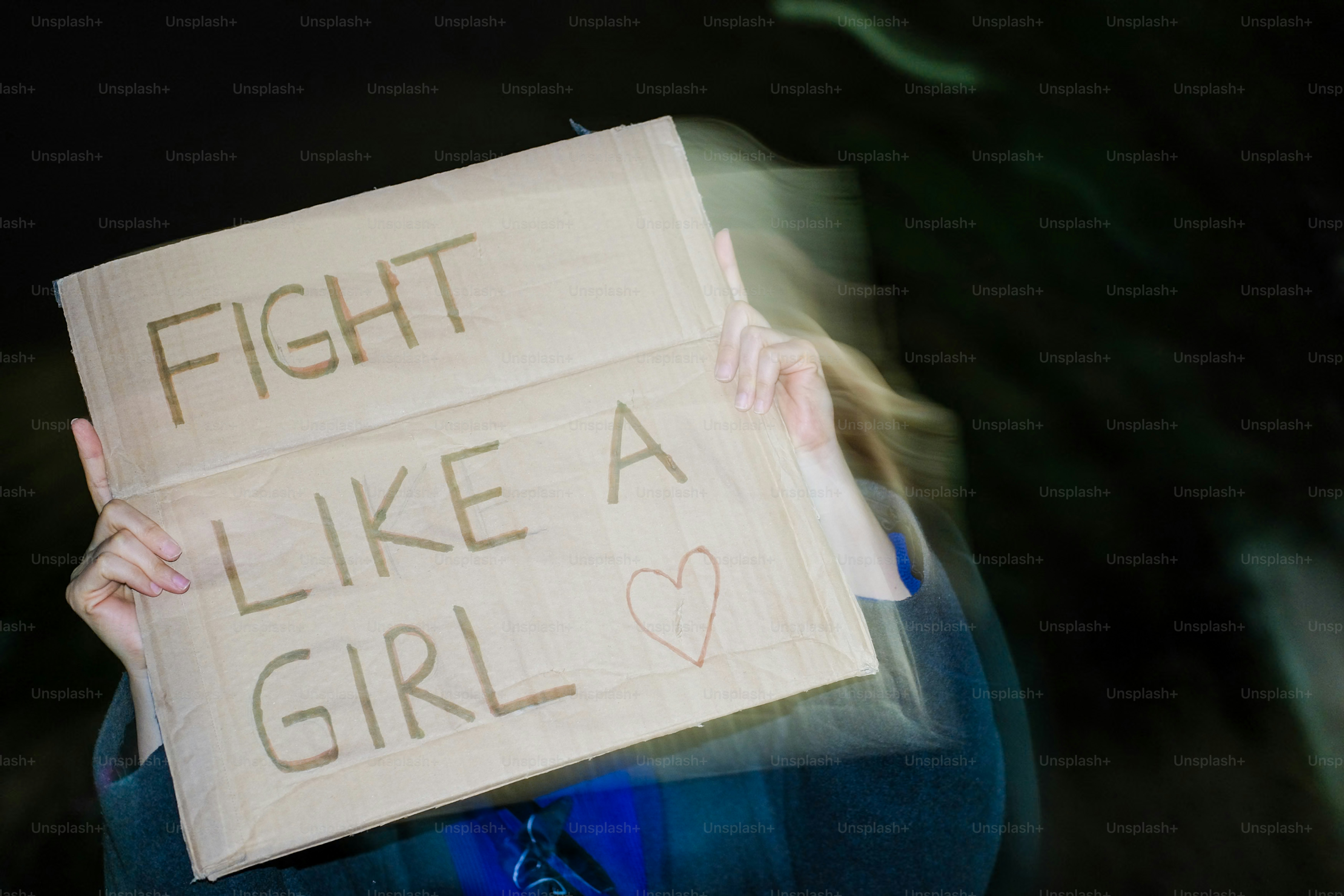 Personne tenant une pancarte où il est écrit « bats-toi comme une fille »