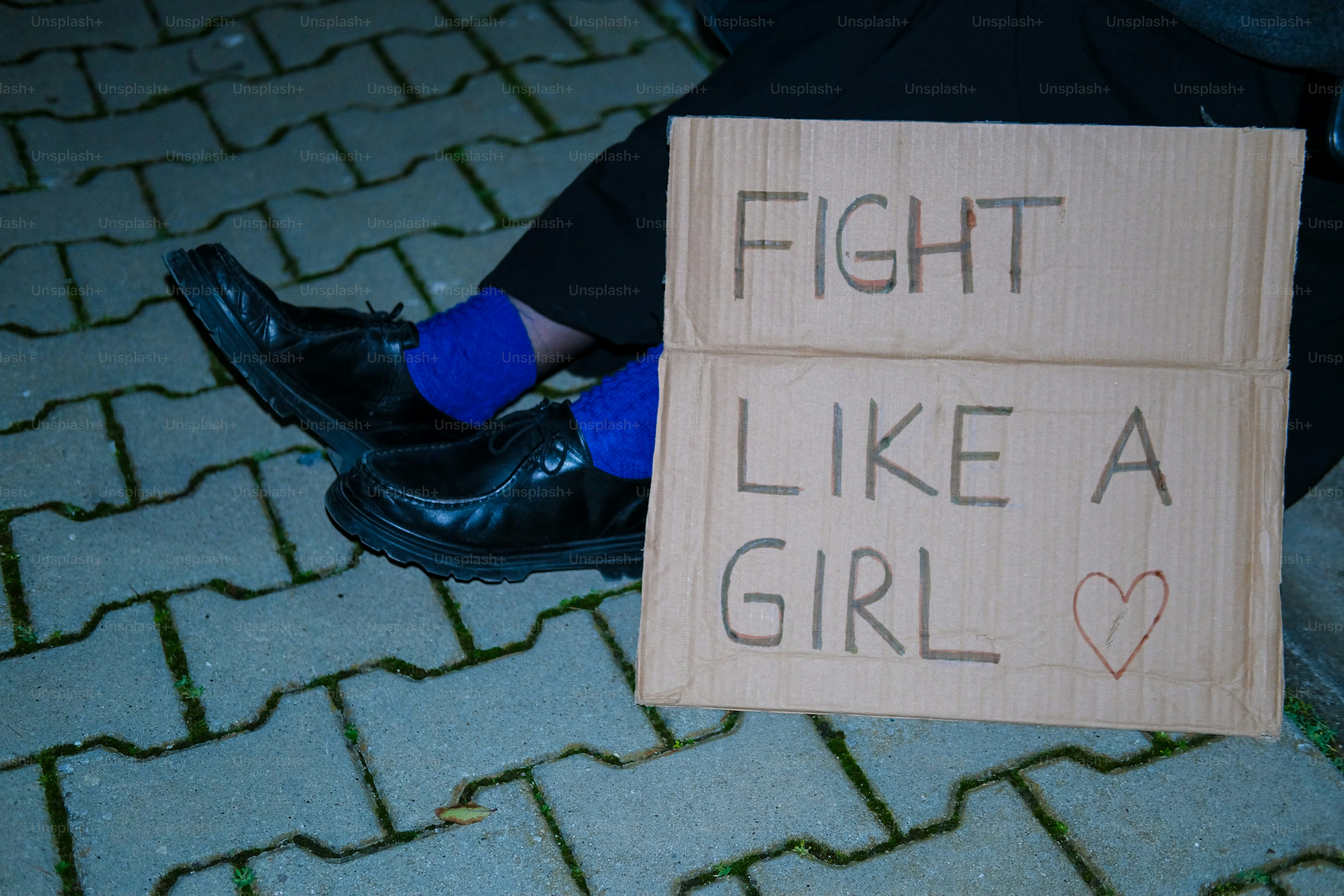 Un panneau en carton dit « bats-toi comme une fille » avec du cœur.