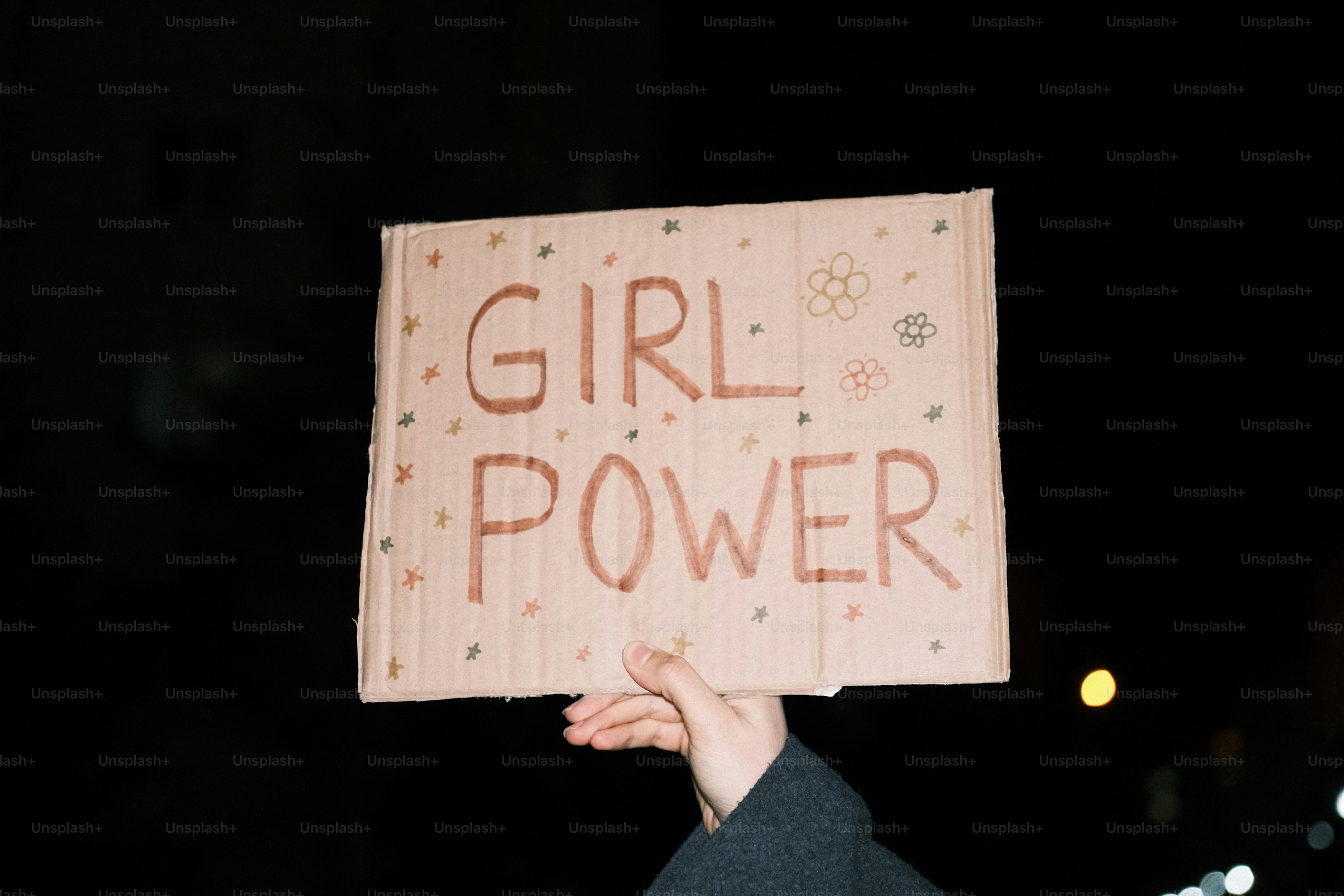 Main tenant un panneau « girl power » avec des fleurs
