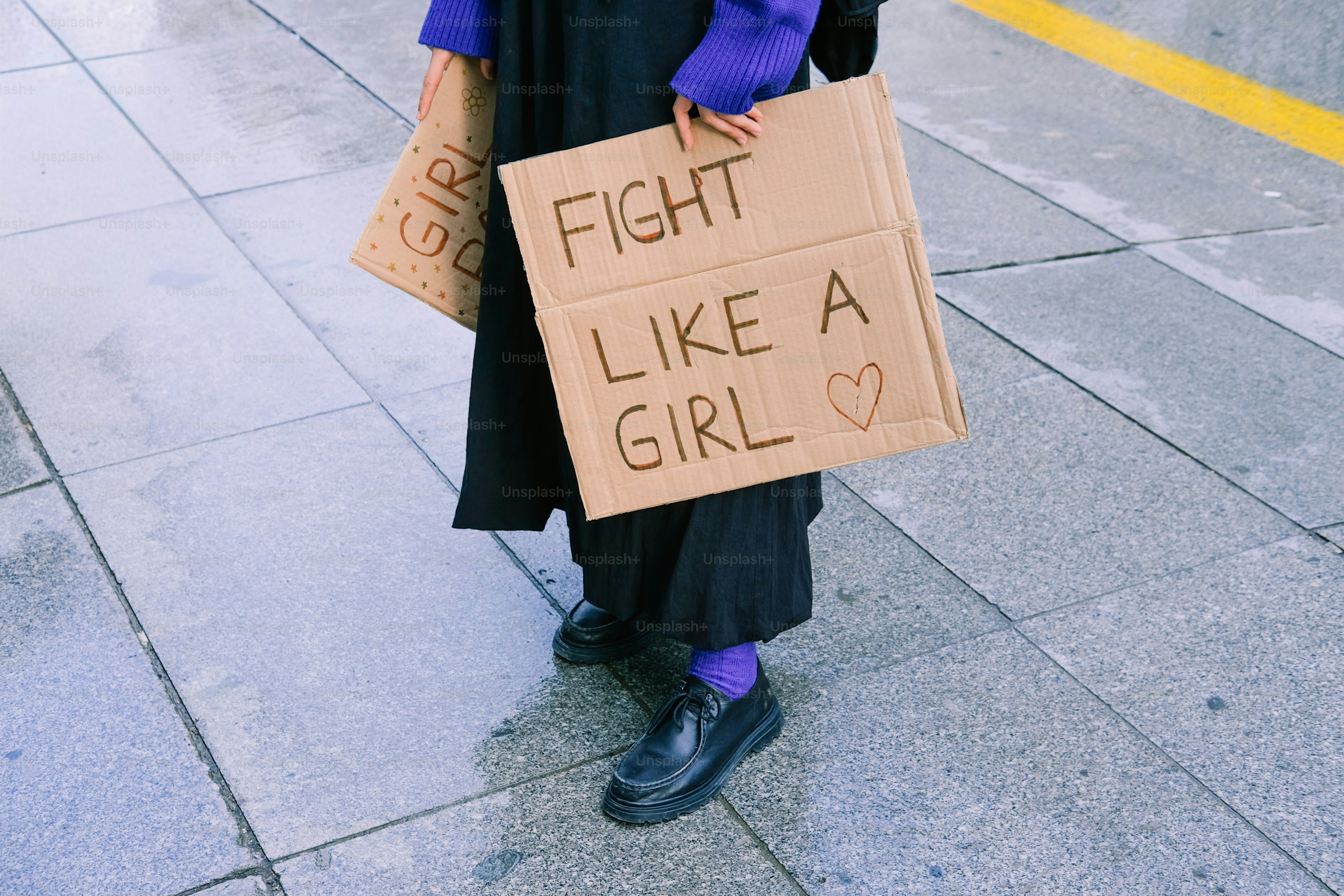 Personne tenant une pancarte de protestation qui dit se battre comme une fille