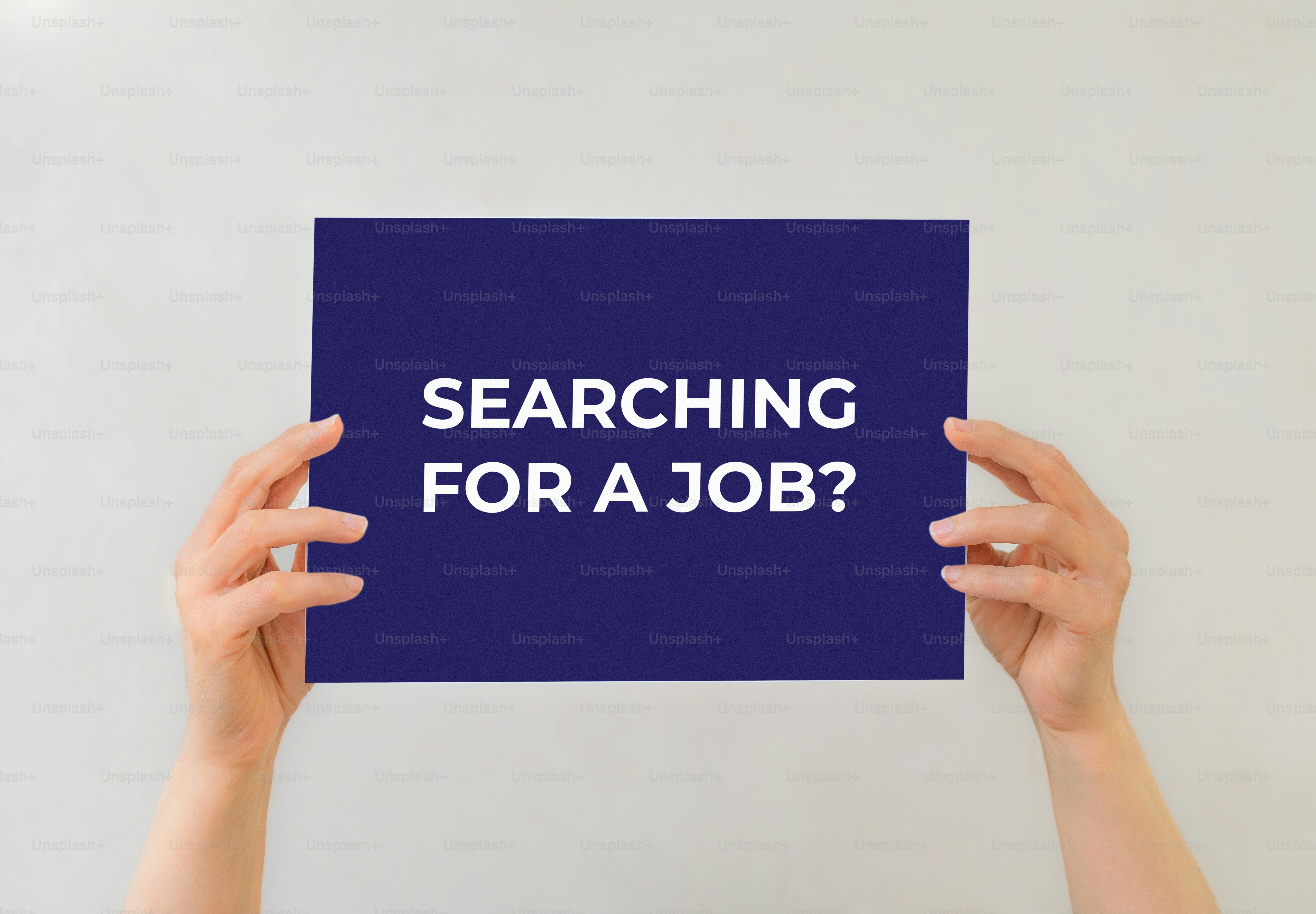 Hands hold a sign that says "searching for a job?"