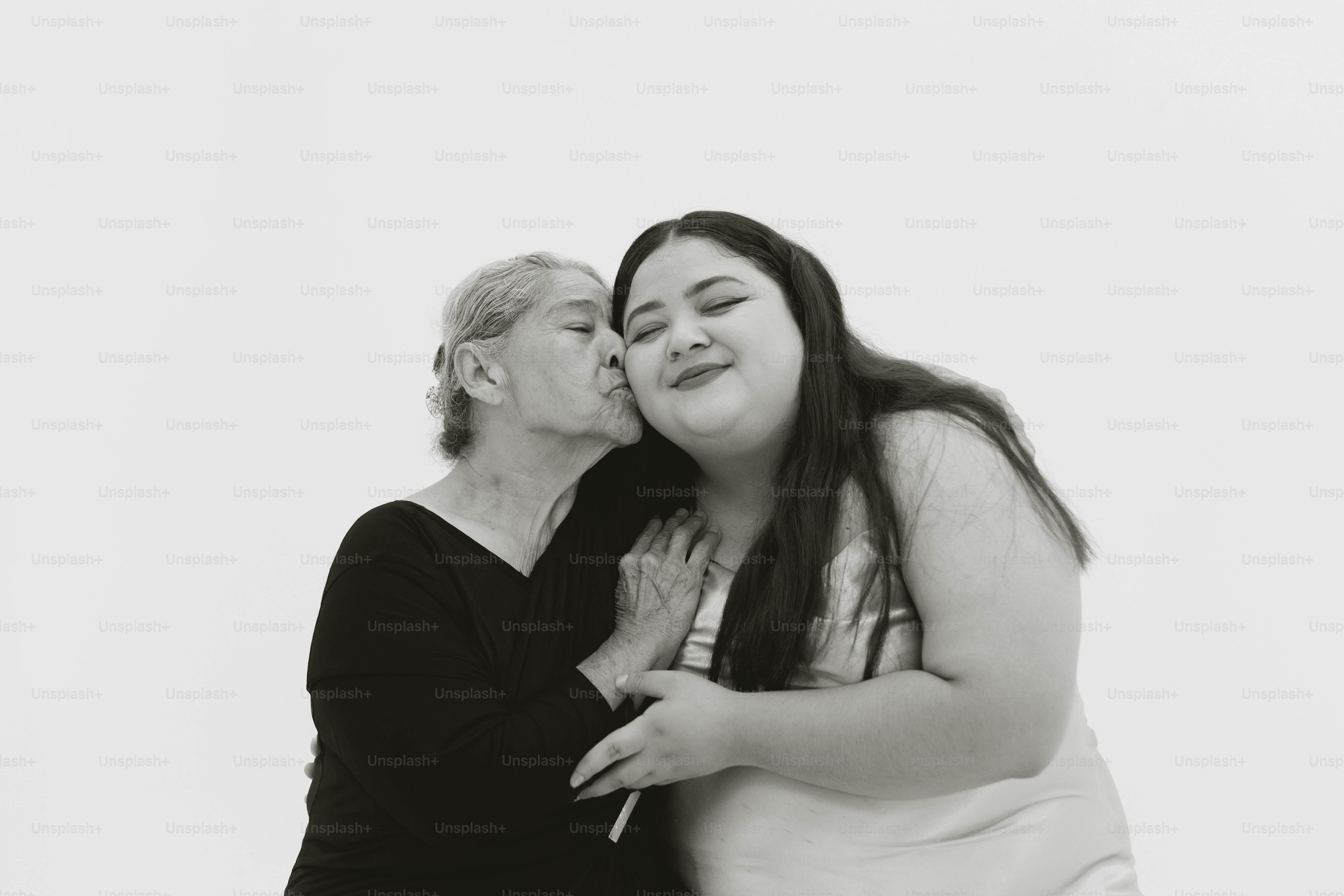 Eine ältere Frau küsst eine jüngere Frau auf die Wange.