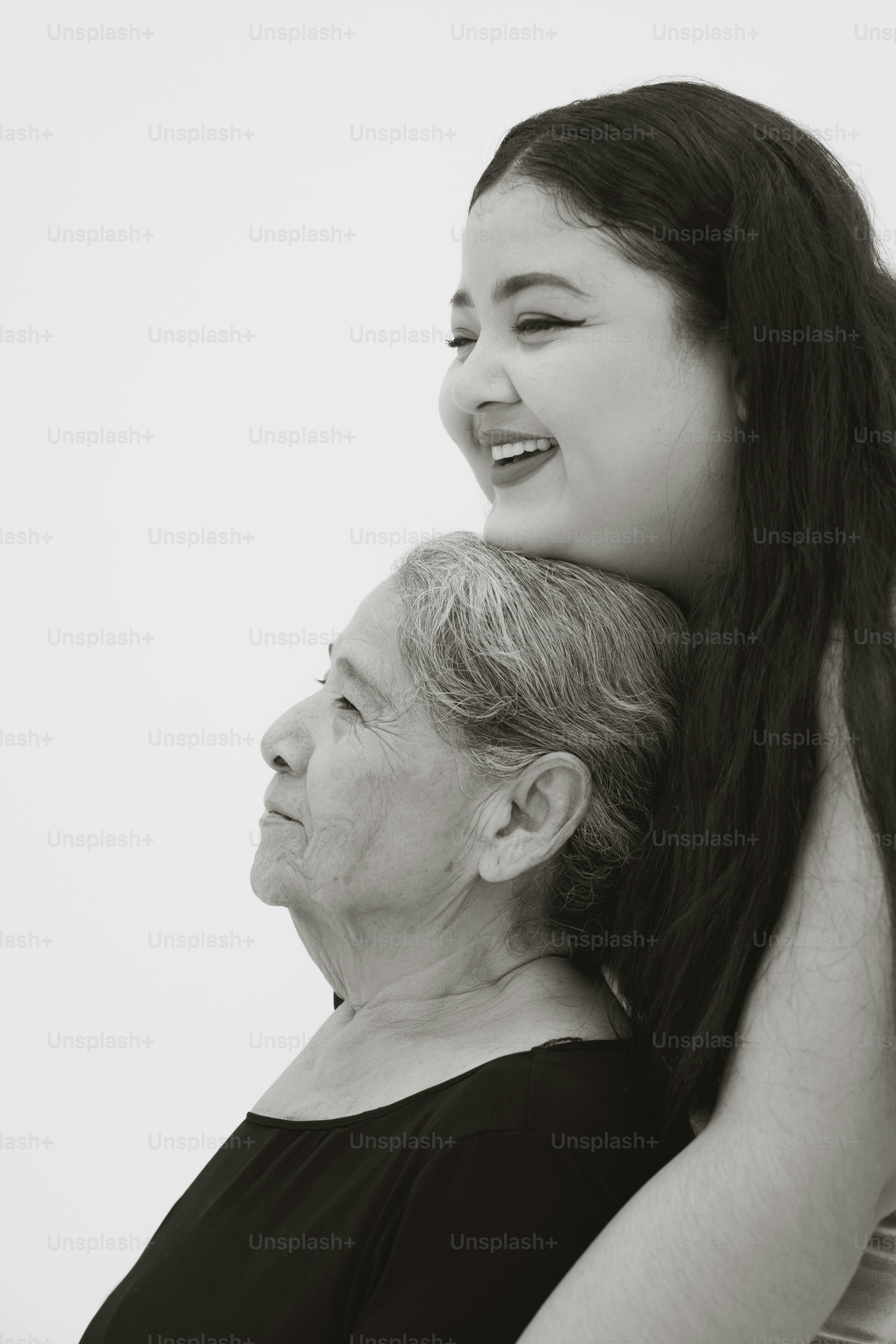 Eine junge Frau umarmt eine ältere Frau von hinten.