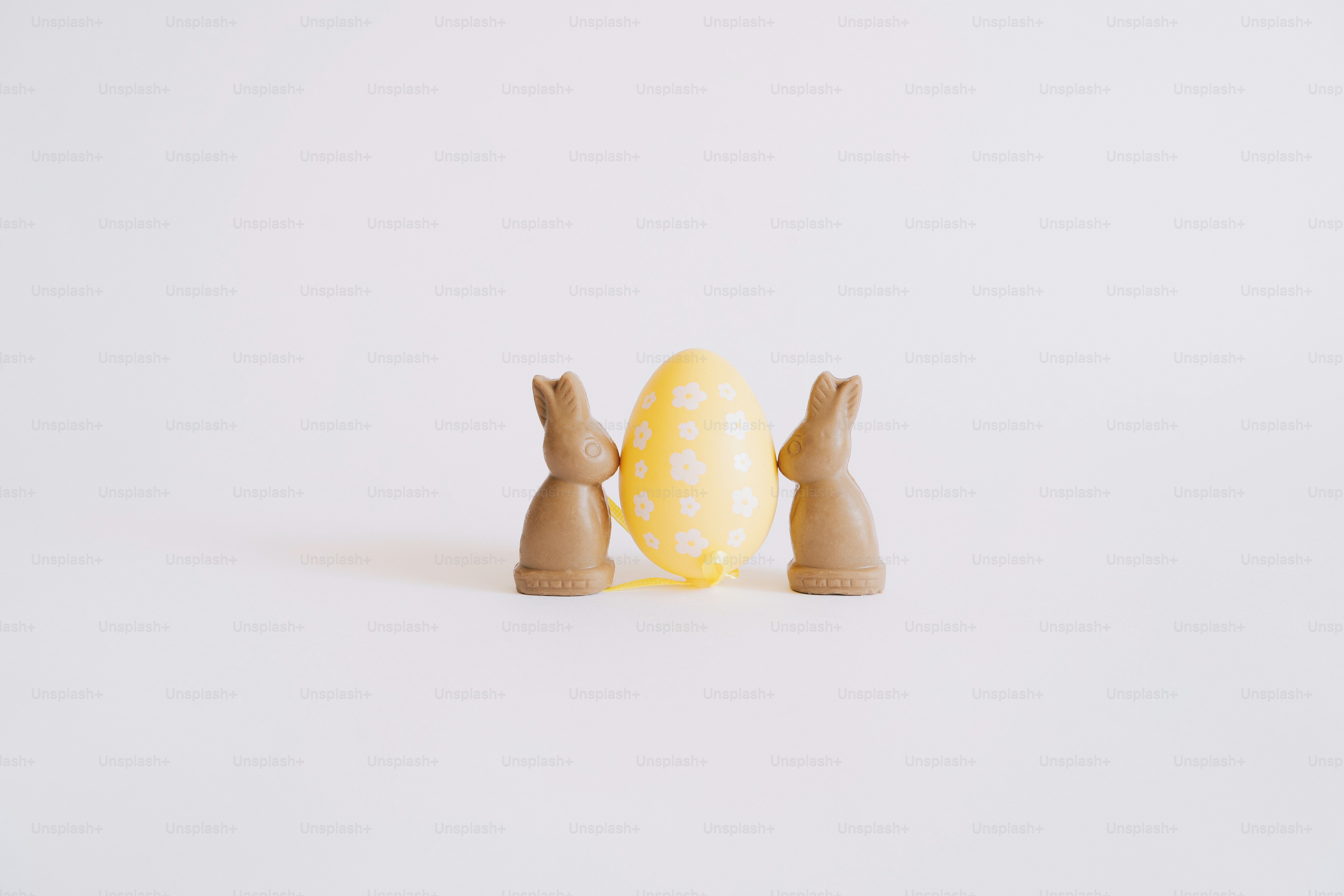 Two chocolate bunnies flank a yellow easter egg