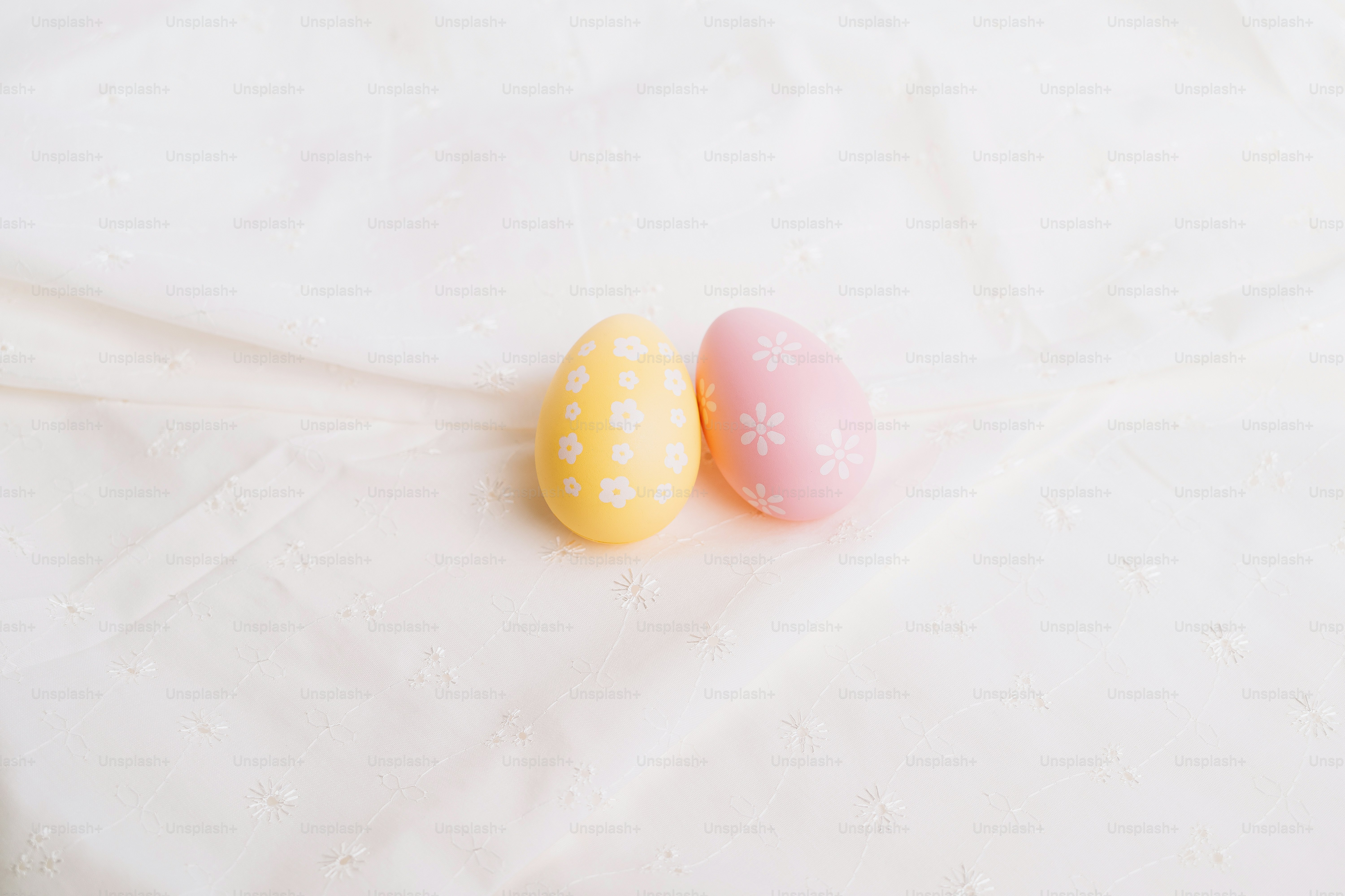 Two pastel easter eggs on a white cloth