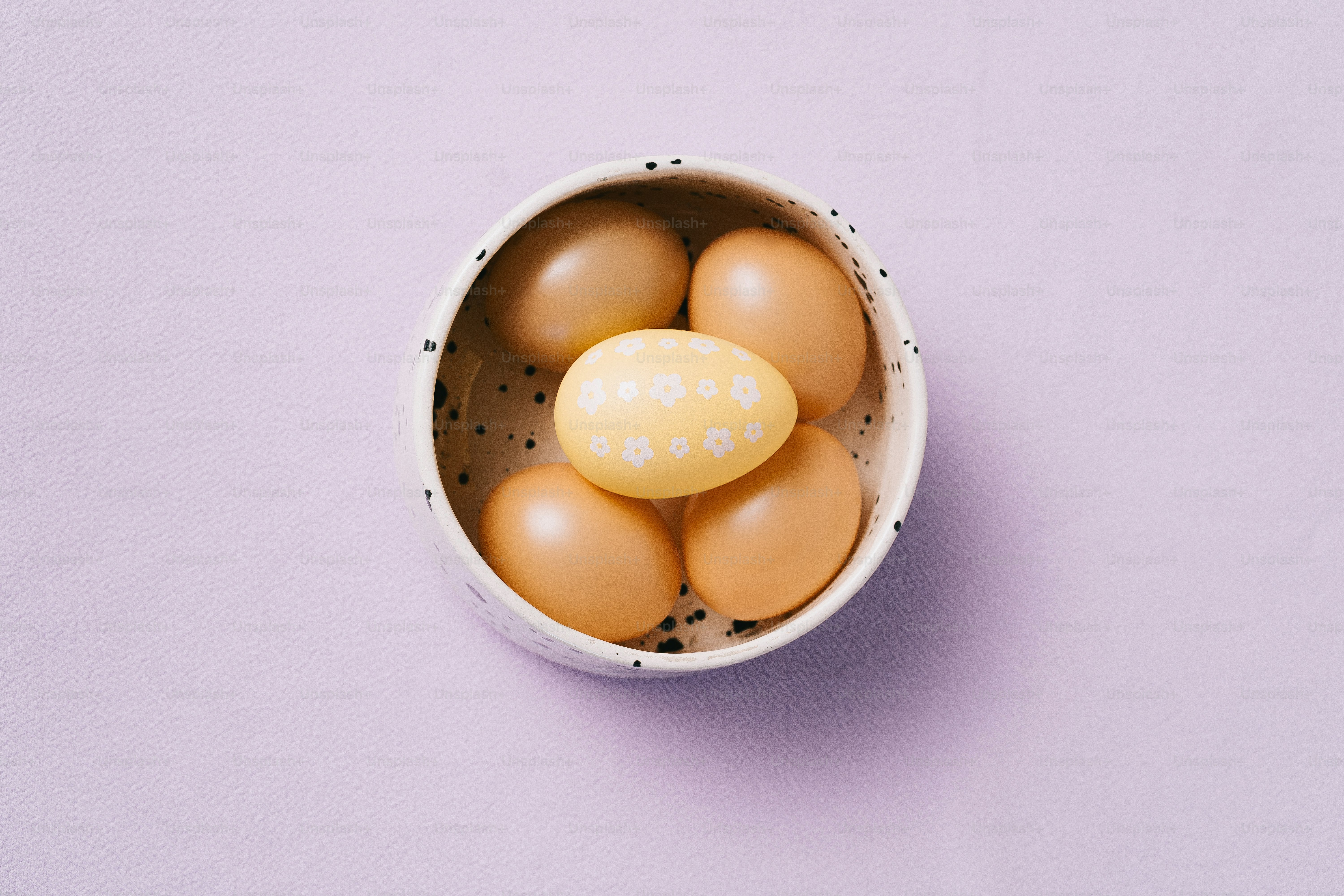 A bowl of brown eggs with one decorated egg.
