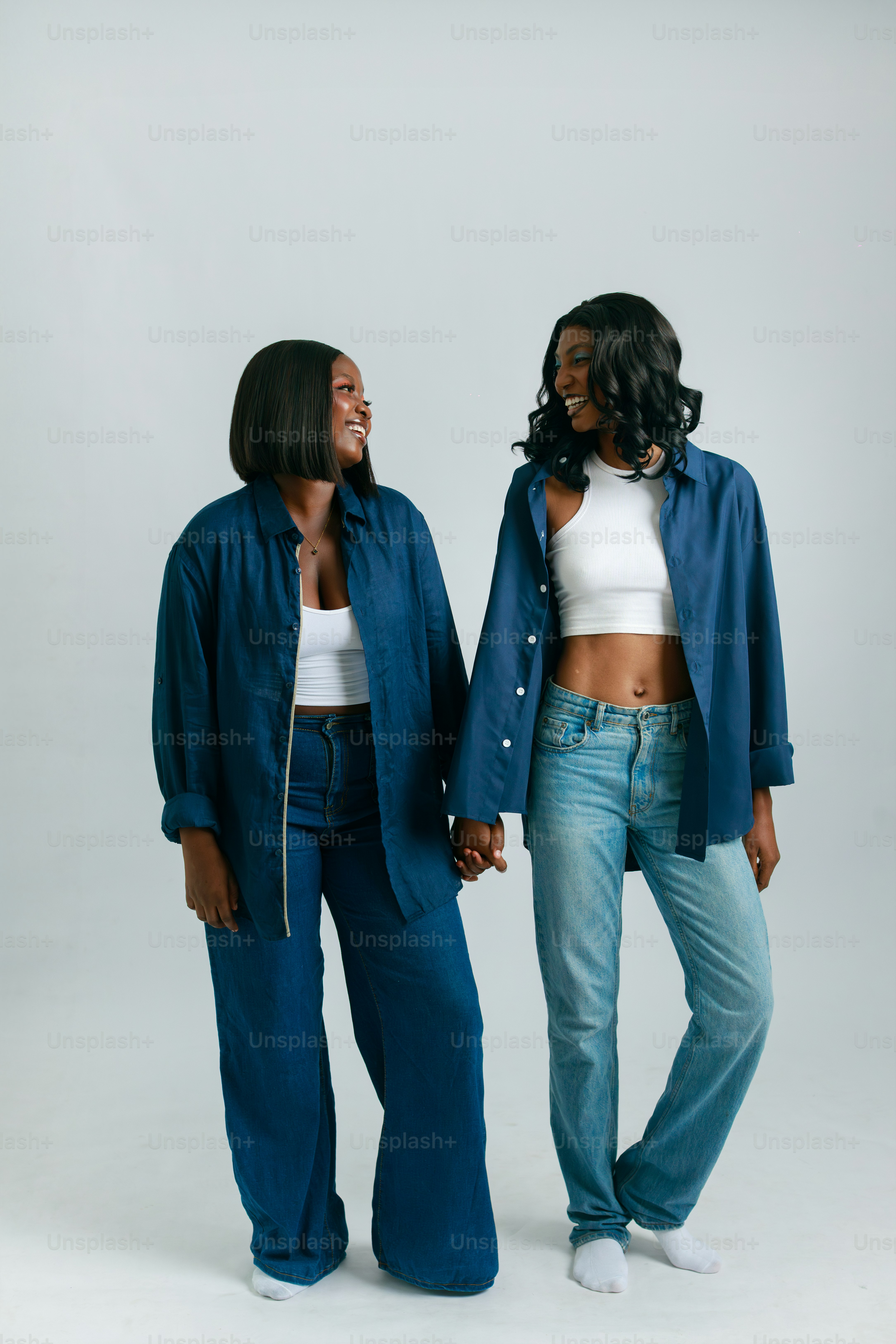 Two women in denim holding hands and smiling