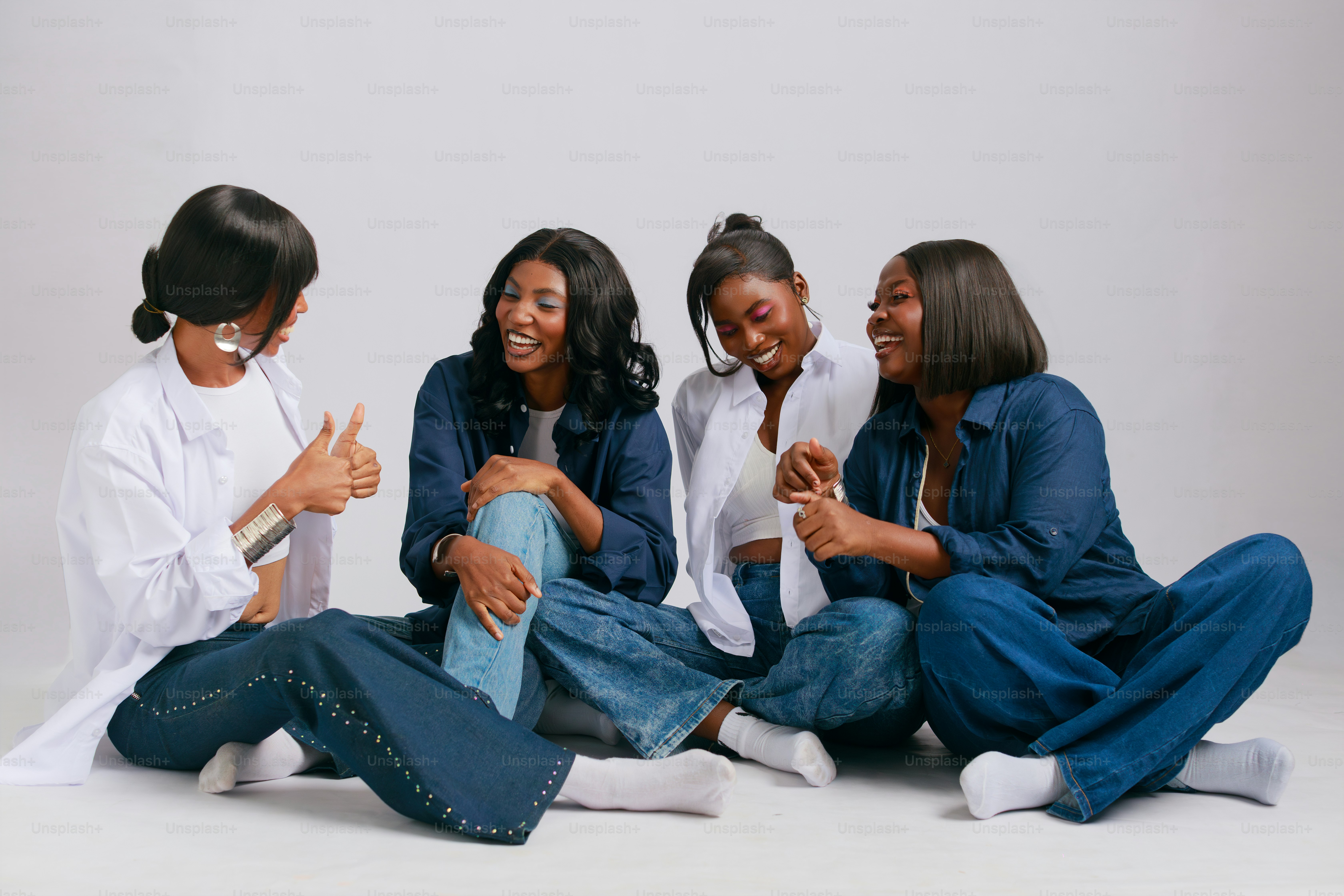Four women in denim and white shirts laughing together