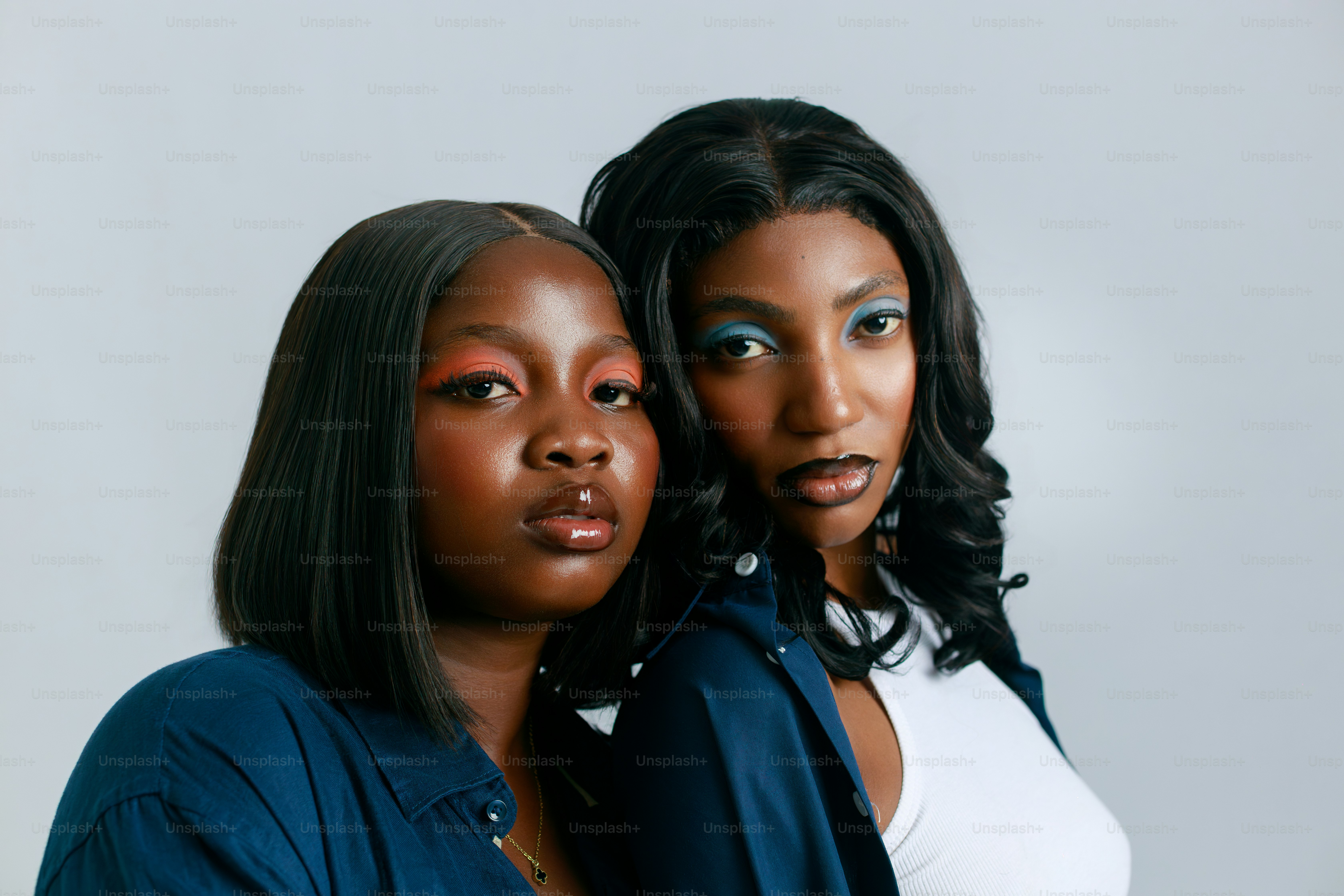 Two young women with vibrant makeup against a white background