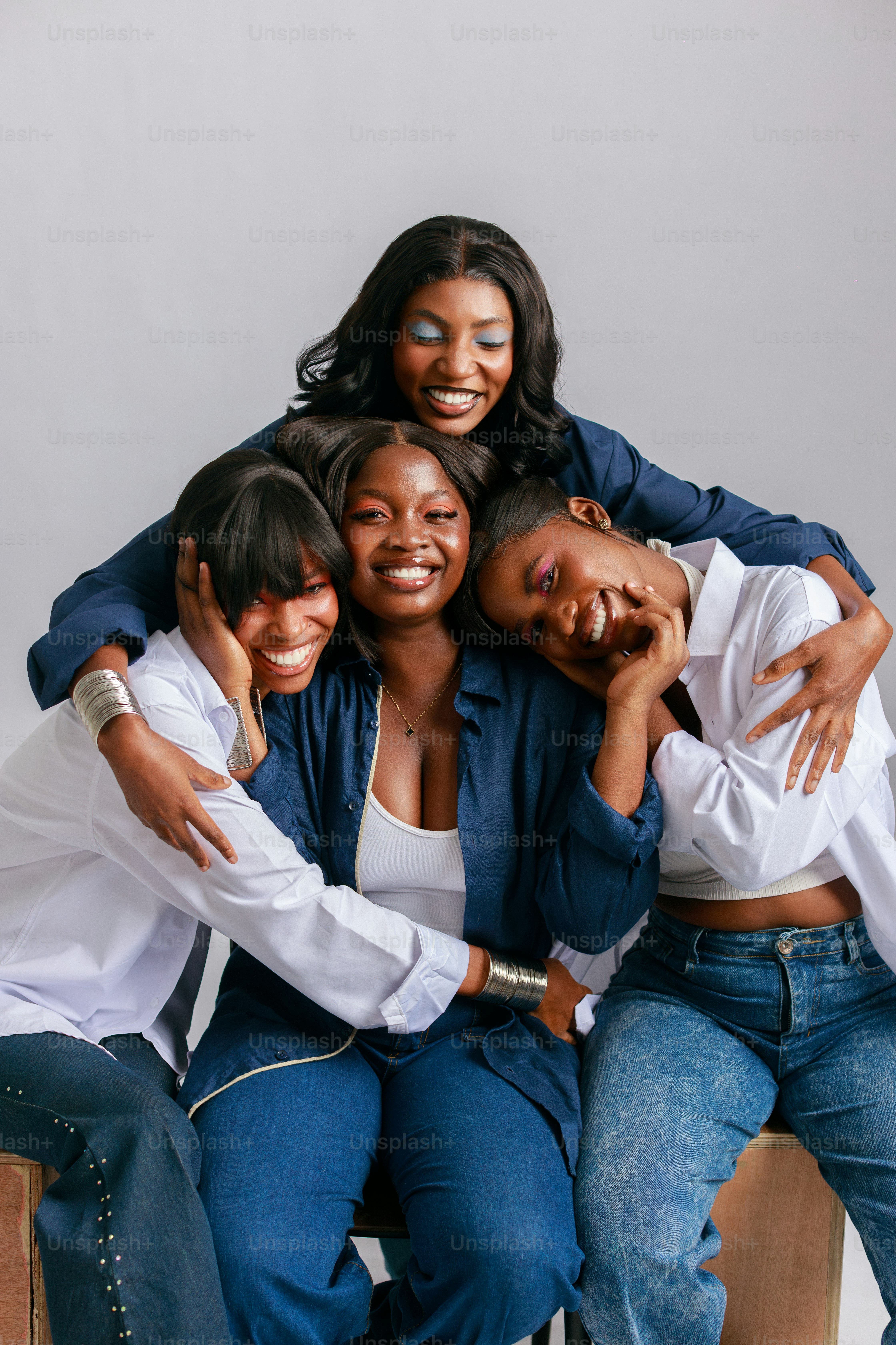 Four smiling women embracing each other on a white background