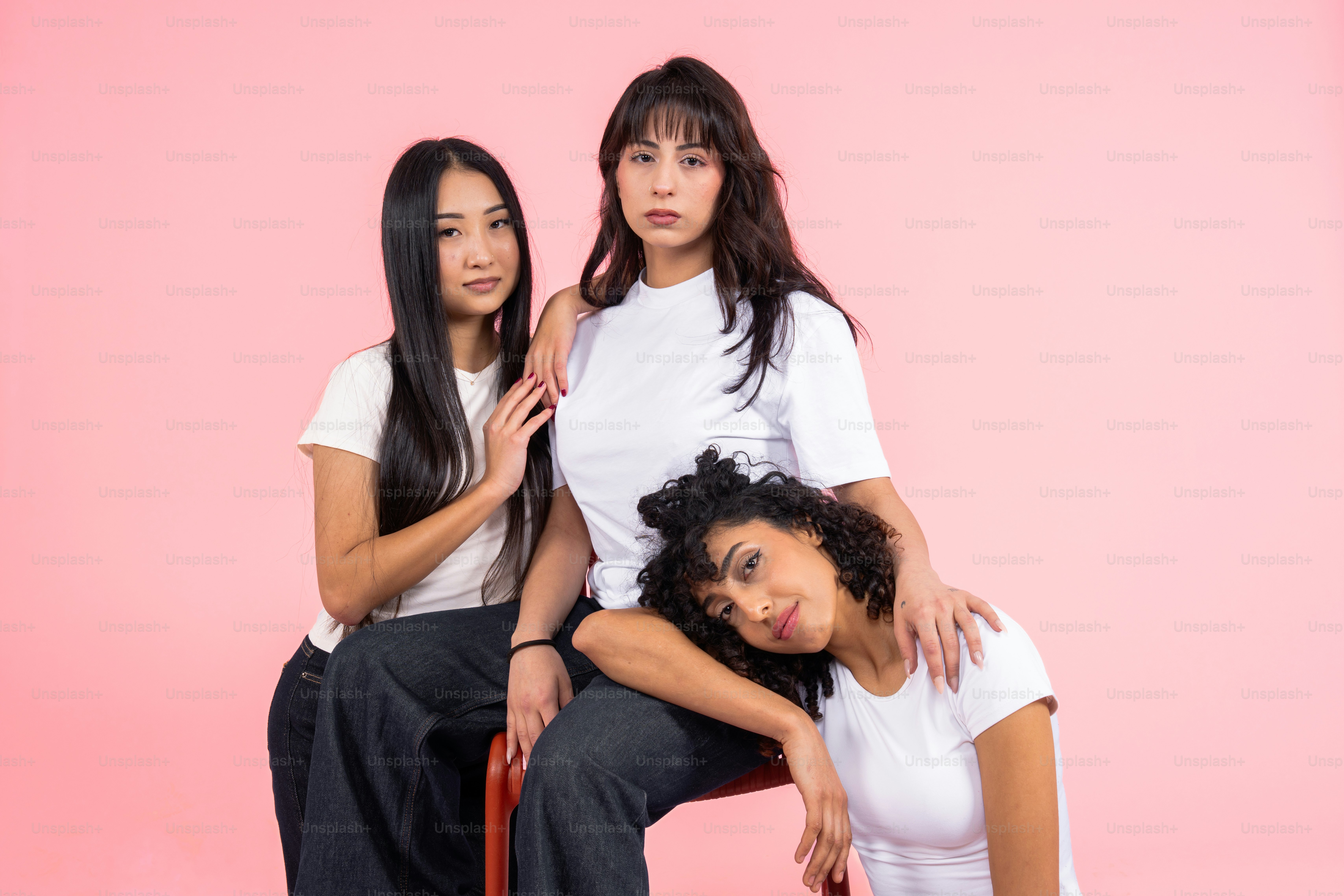 Three diverse women posing against a pink background