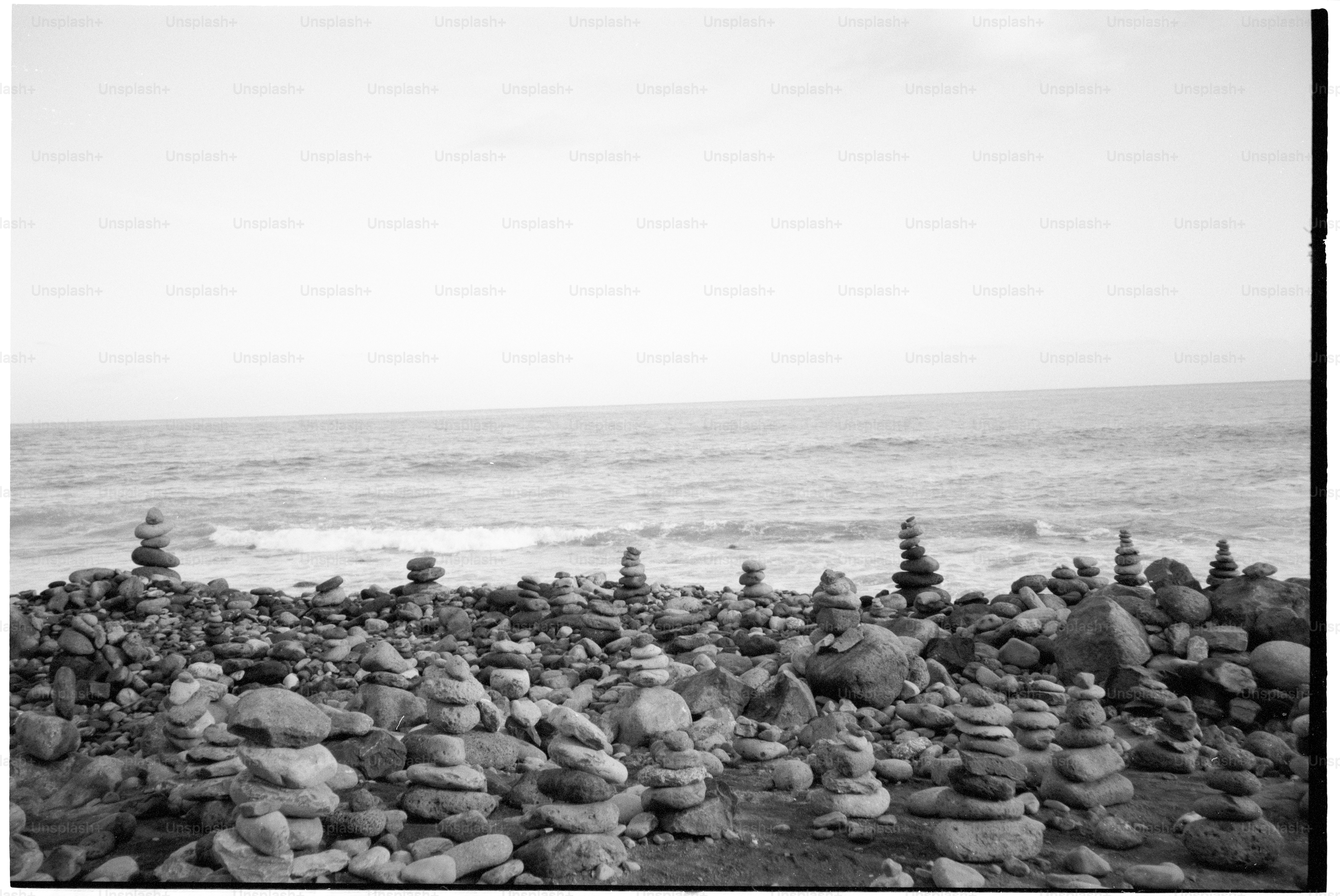 Stone cairns on a rocky shore by the ocean.