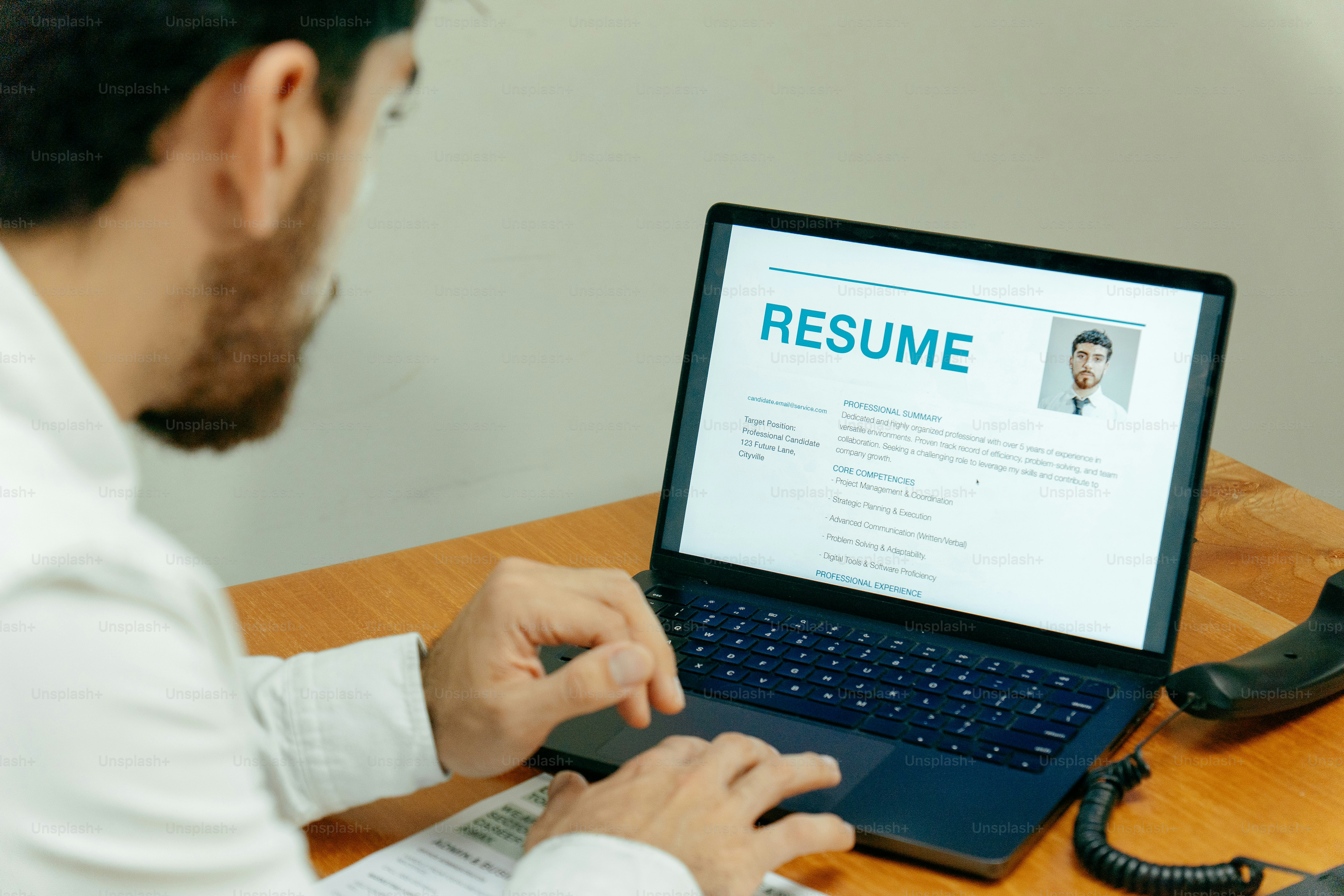 Man typing on laptop displaying resume