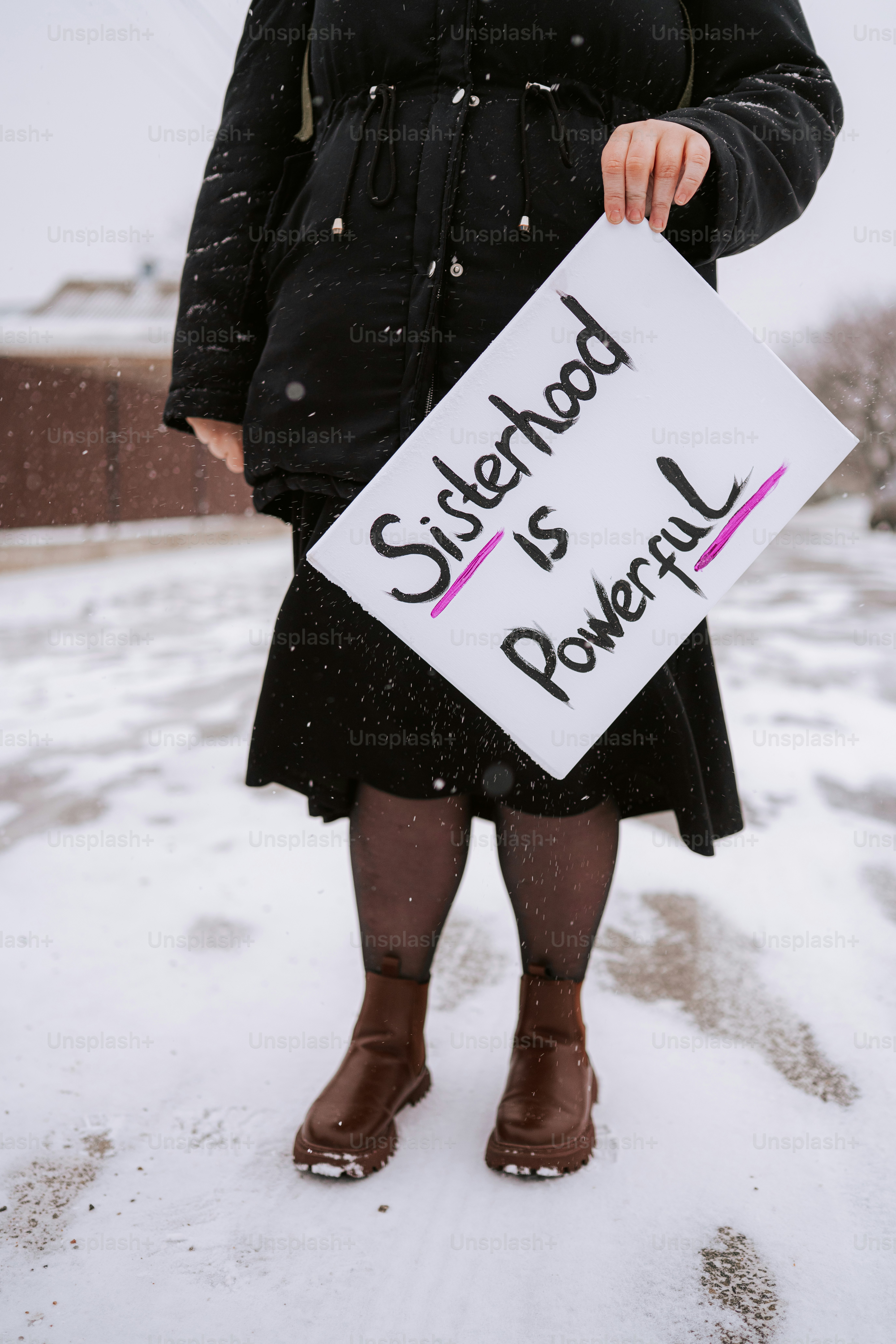 Woman holds sign that says sisterhood is powerful